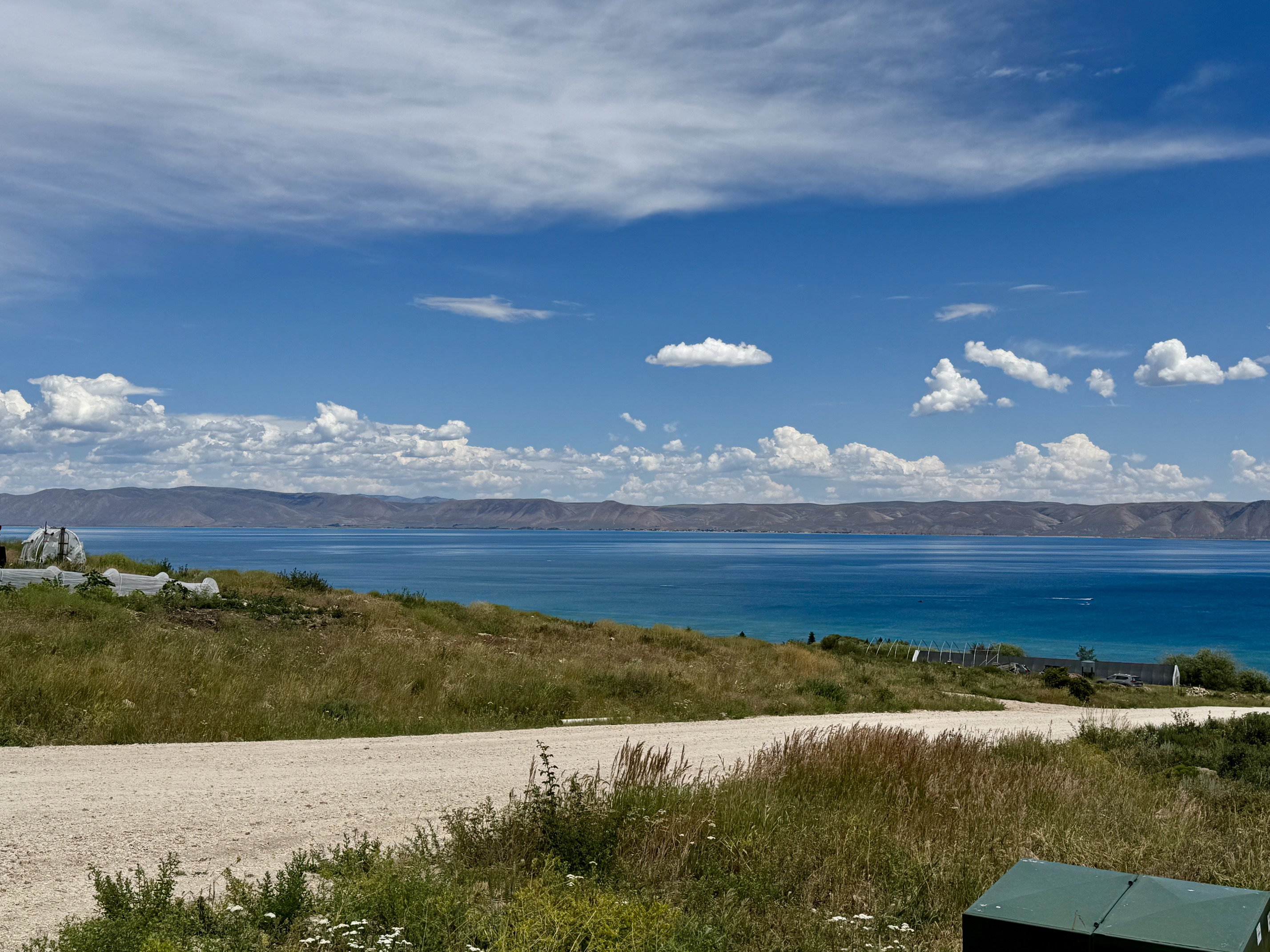 Expansive water frontage with a vibrant blue-green hue, framed by distant mountains and a clear sky