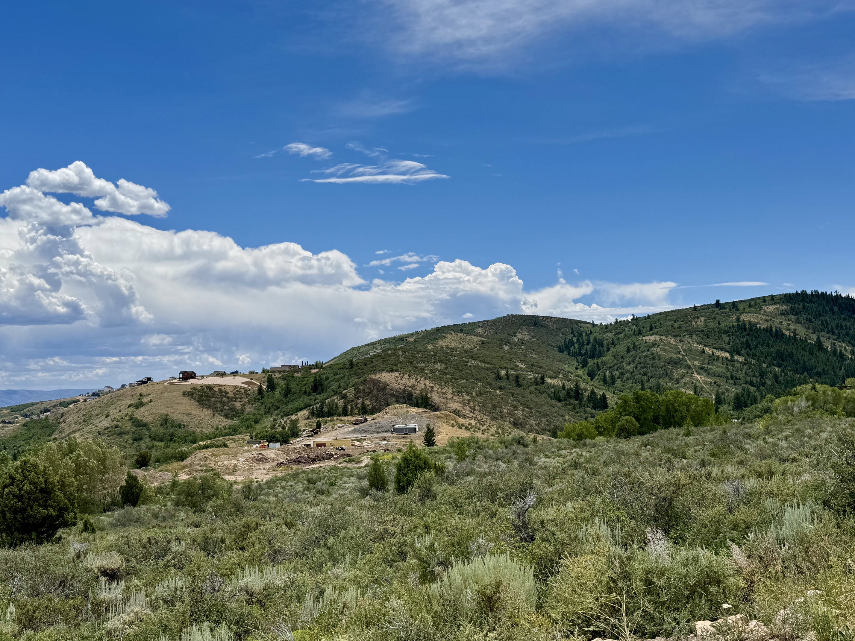 Expansive mountainous landscape featuring distant residential structures under construction