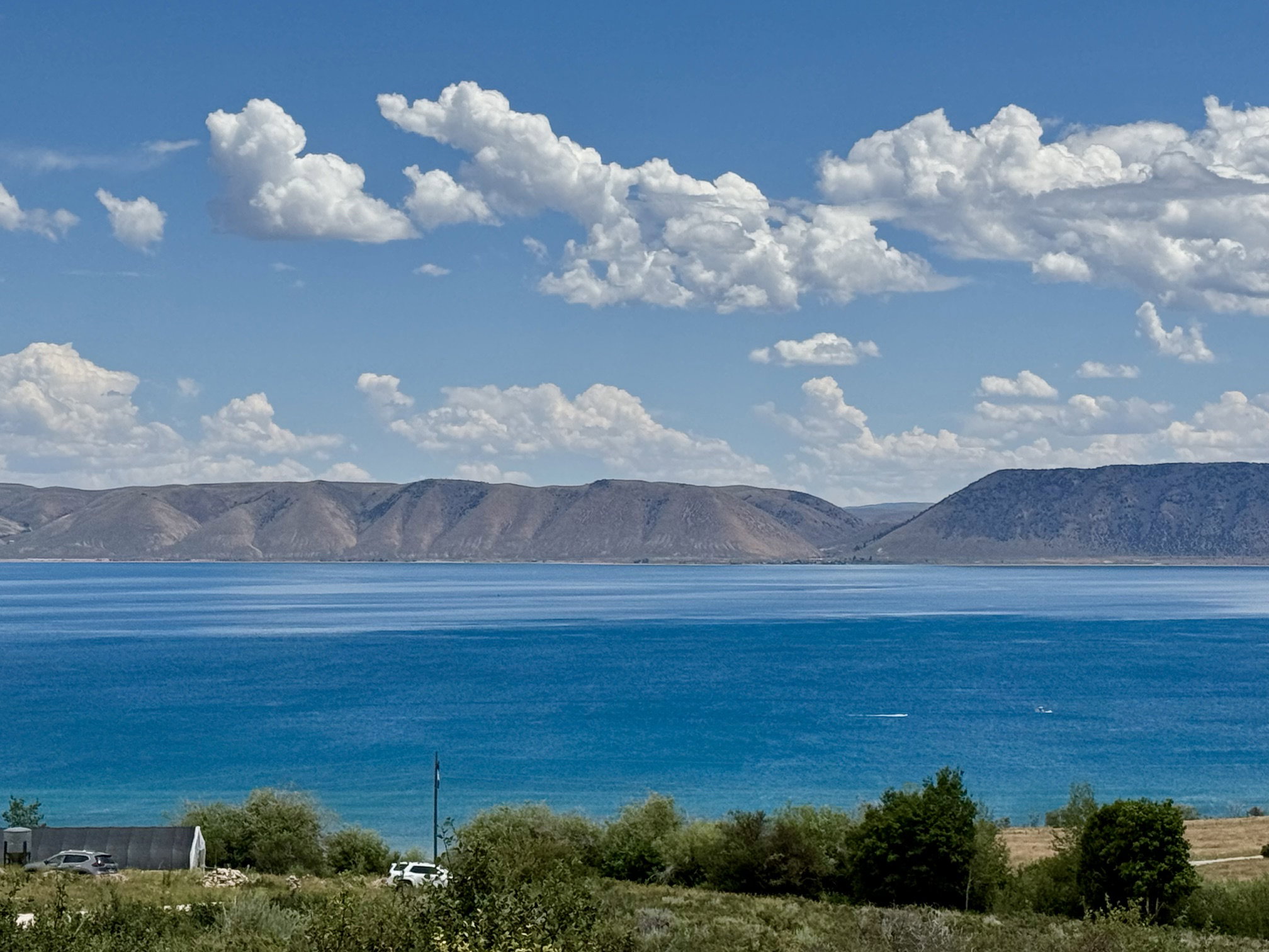 Expansive water frontage with mountain backdrop, surrounded by natural vegetation
