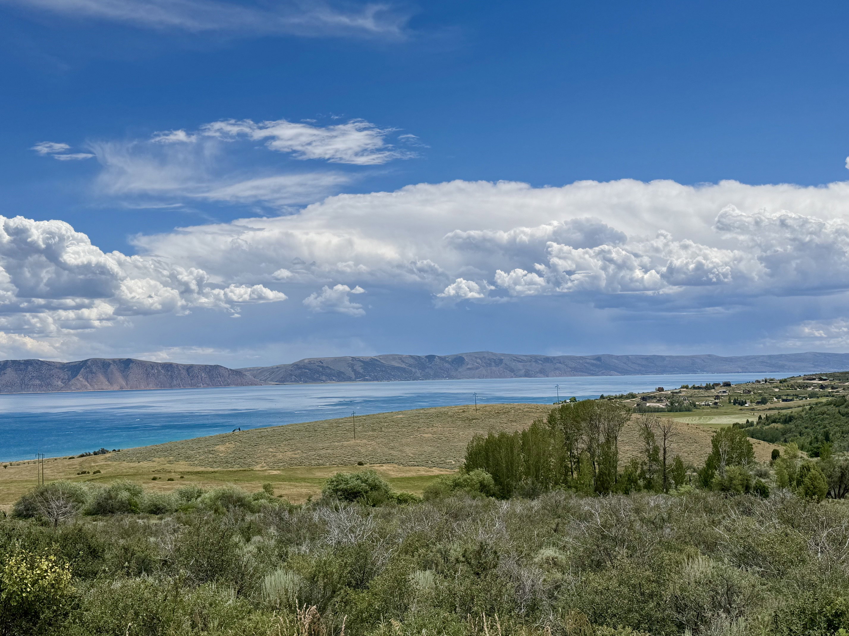 Expansive landscape featuring a large body of water, distant mountains, and varied natural terrain