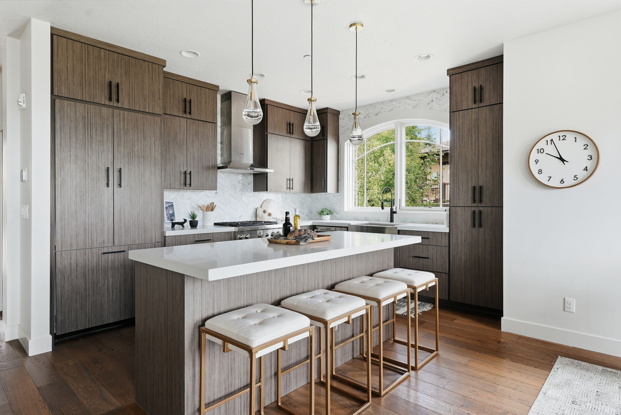 Kitchen featuring wood-finish cabinetry, a large center island with a white countertop, a built-in refrigerator, and a curved arch window above the sink