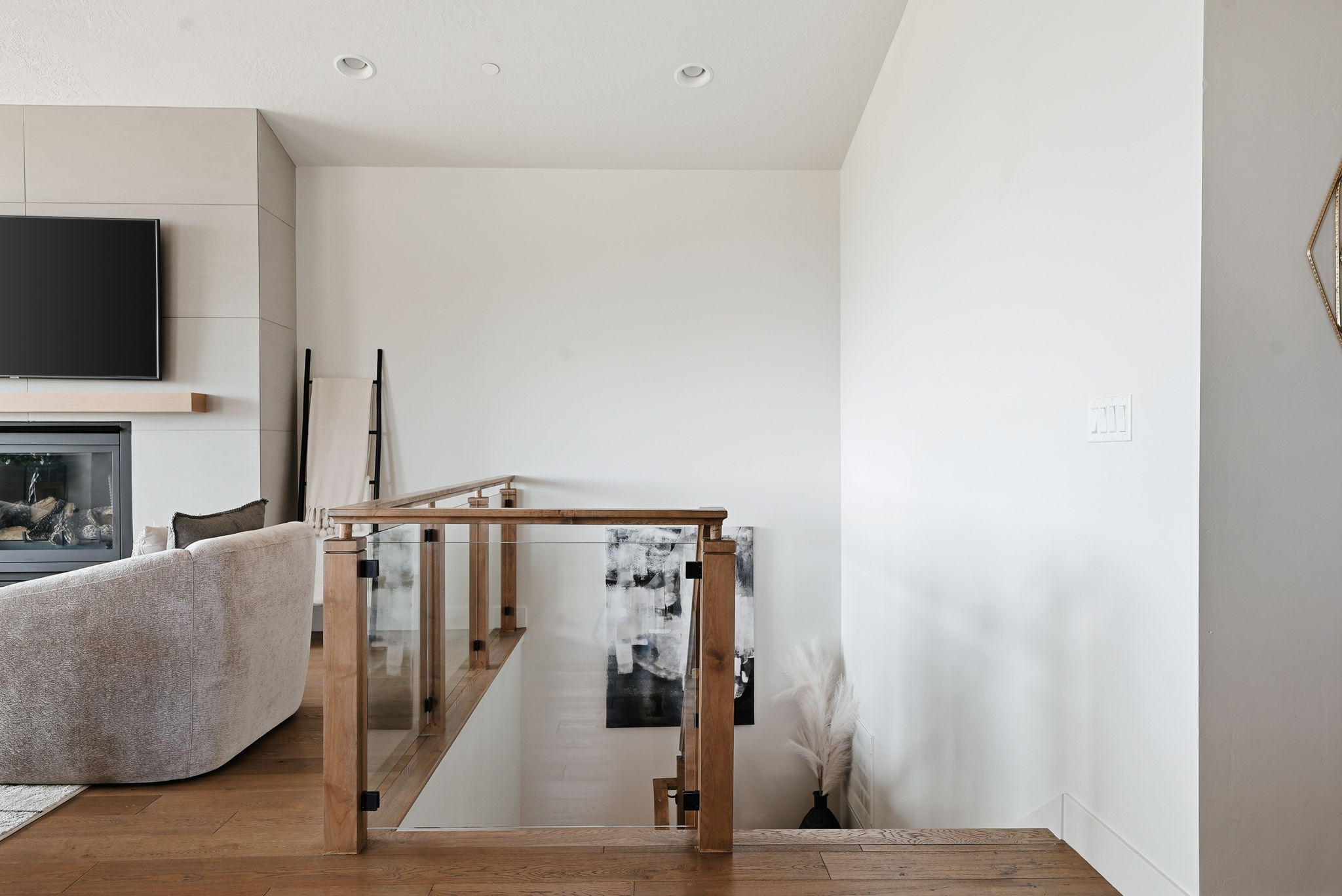 Hardwood flooring, a glass and wood-finish stair railing, and a contemporary fireplace with solid wood mantel