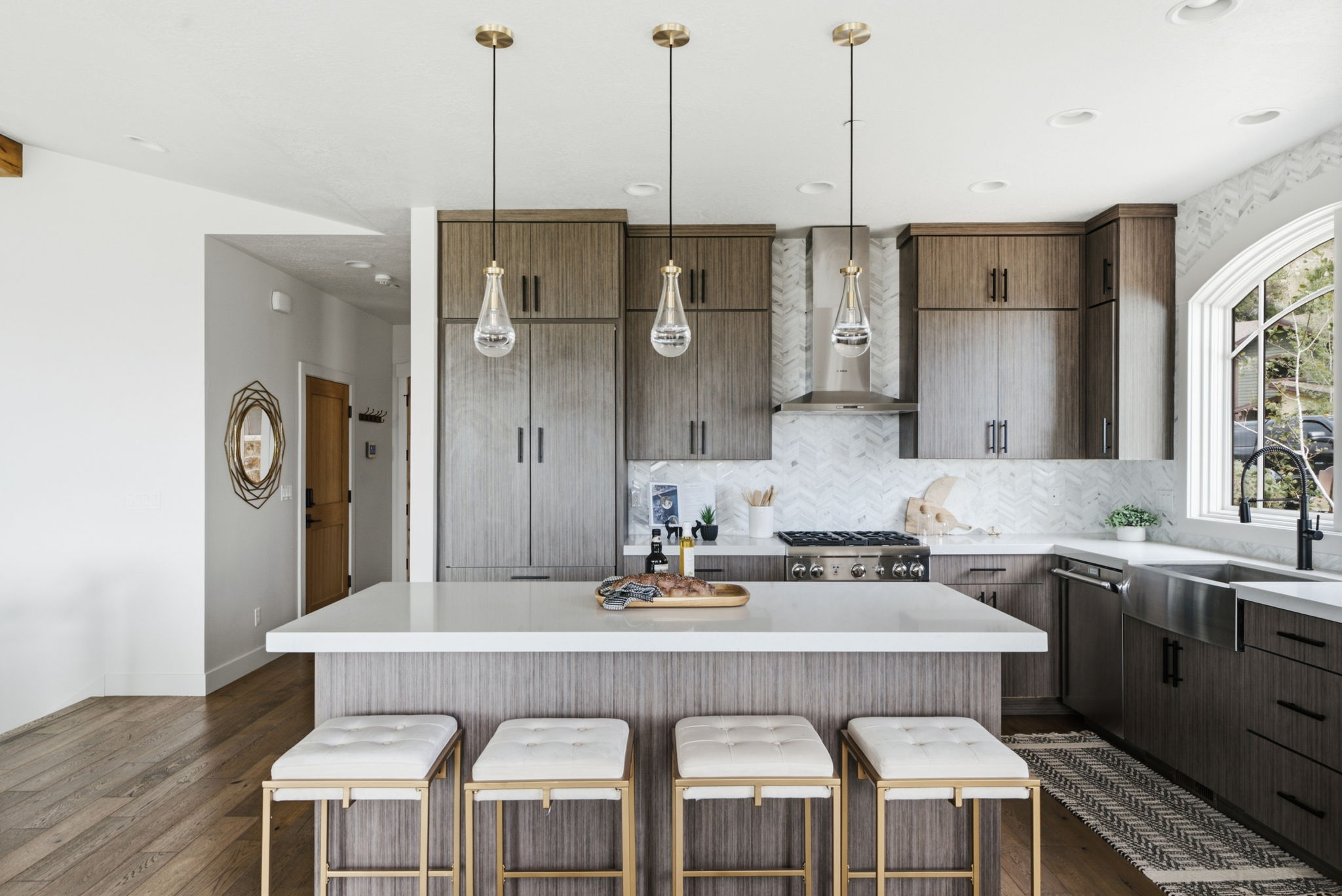 Contemporary kitchen featuring wood-finish cabinetry, a large center island with seating, stainless steel appliances, and a farmhouse sink