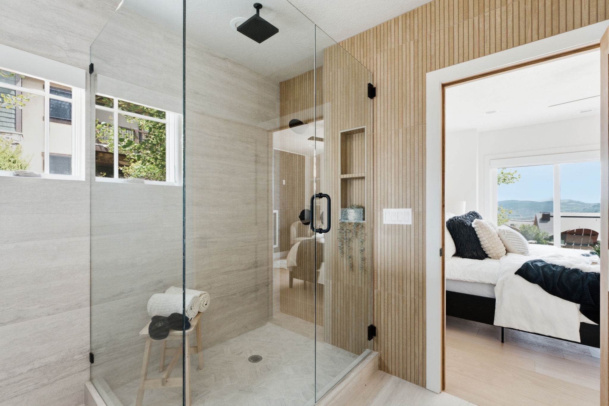 Spacious glass-enclosed shower featuring a rain showerhead, tiled walls, and a recessed niche