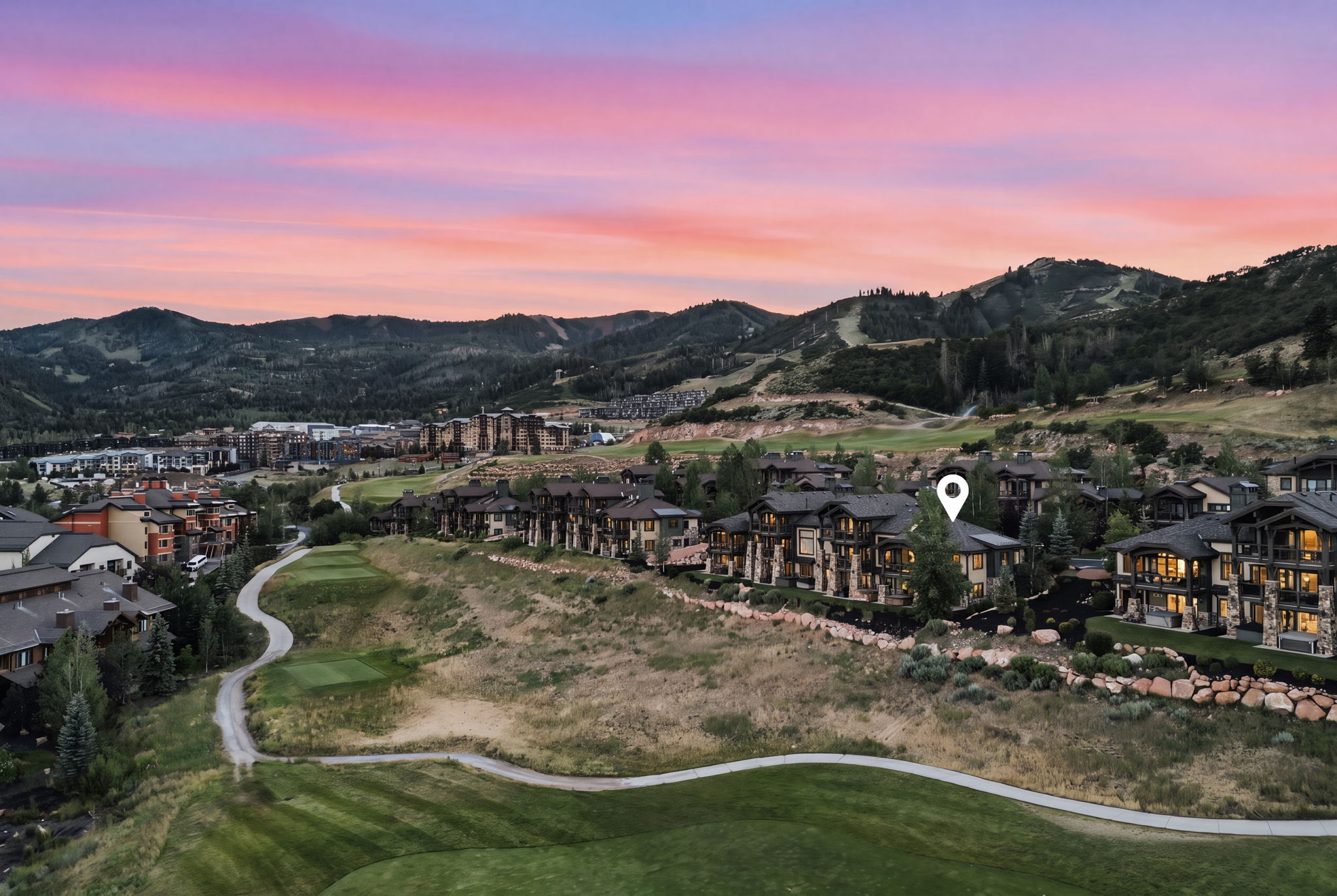Aerial perspective featuring a residential community amidst a mountainous landscape with a golf course