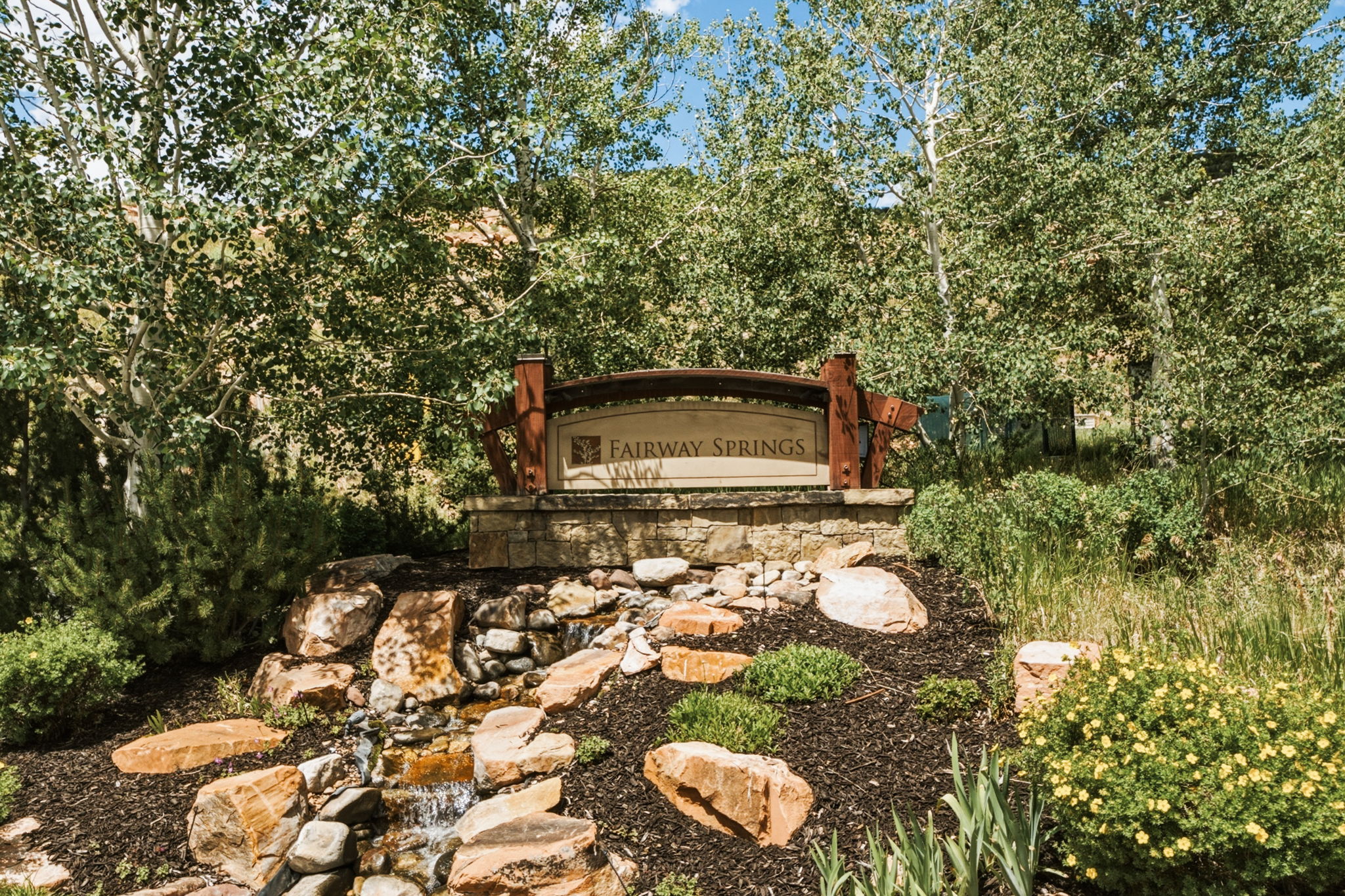 Fairway Springs monument sign, waterfall feature with stone base and wood-finish accents