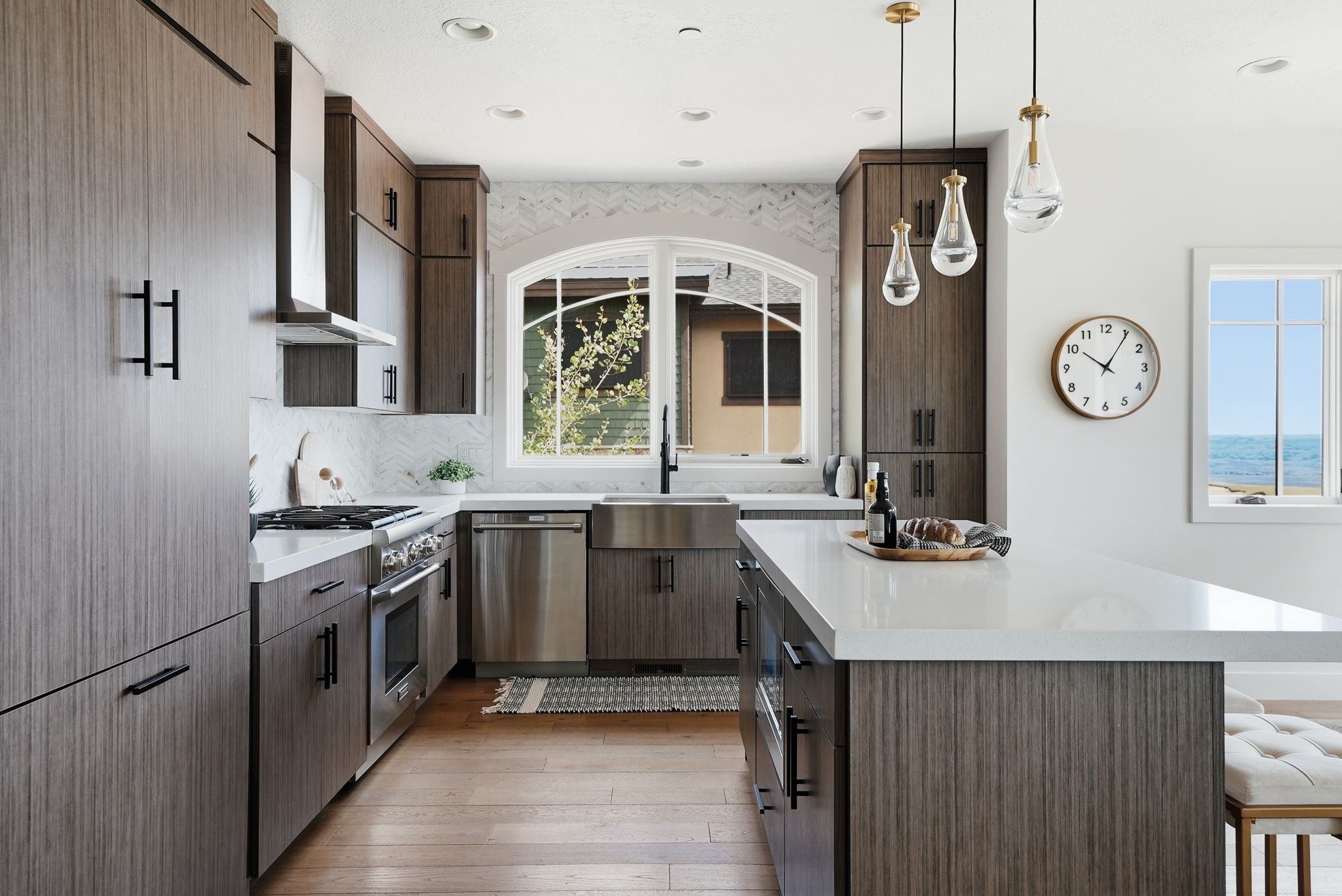 Modern kitchen featuring wood-finish cabinetry, stainless steel appliances, a white quartz island, and wood-finish flooring