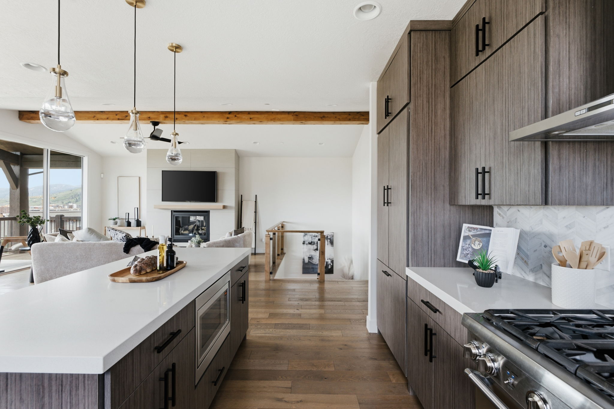 Open-concept kitchen and living area featuring a kitchen island, Calacatta marble backsplash, recessed microwave, and new pendant lighting