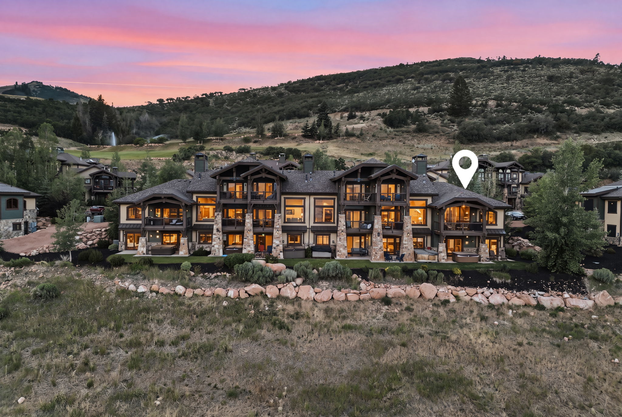 Expansive multi-level structure featuring a stone and siding exterior, multiple balconies, and a distinctive peak roofline
