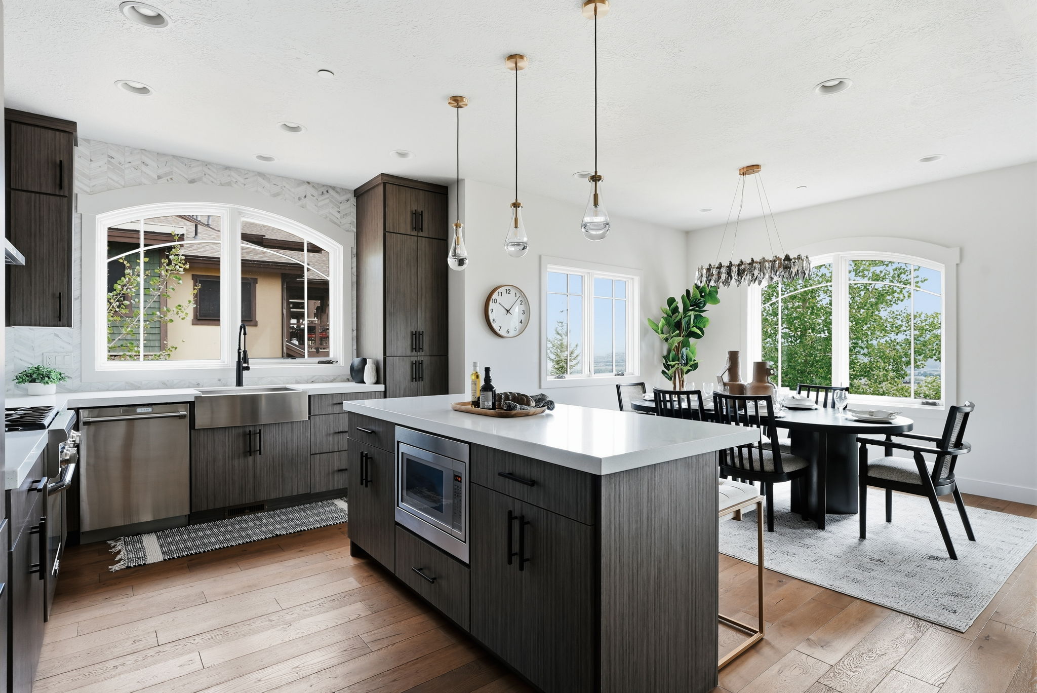Contemporary kitchen featuring dark wood-finish cabinetry, stainless steel appliances, a center island with a built-in microwave, and light countertops