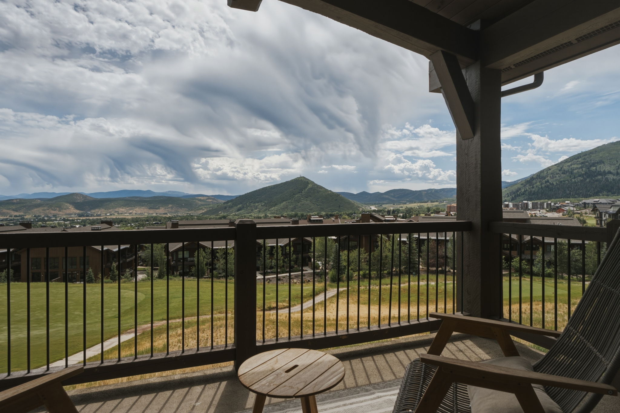 Expansive covered outdoor wood-finish deck, dark metal railings, and sturdy timber support beams