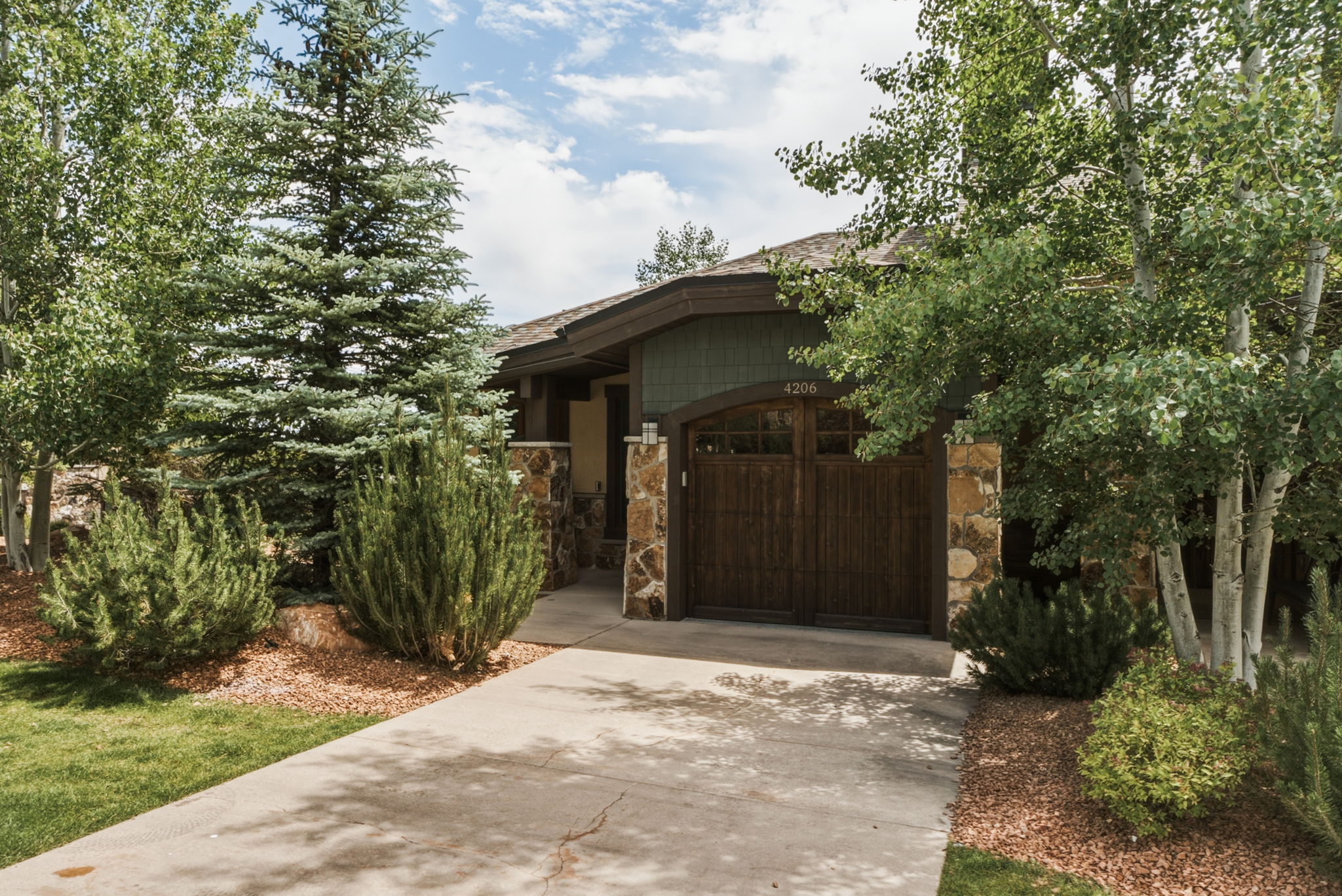 Front entrance, driveway, wood-paneled garage door with arched window accents