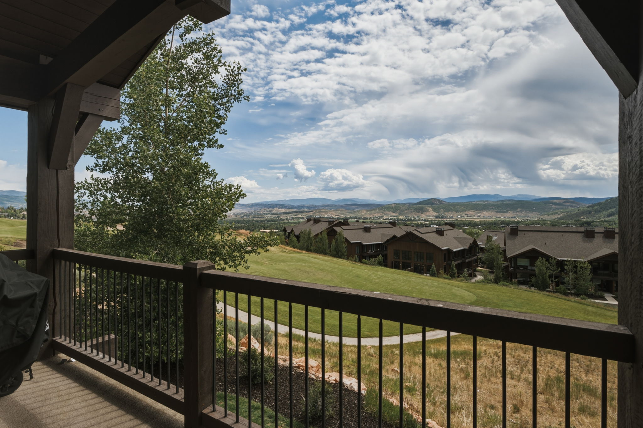 Covered outdoor deck featuring exposed wood beams and a metal railing