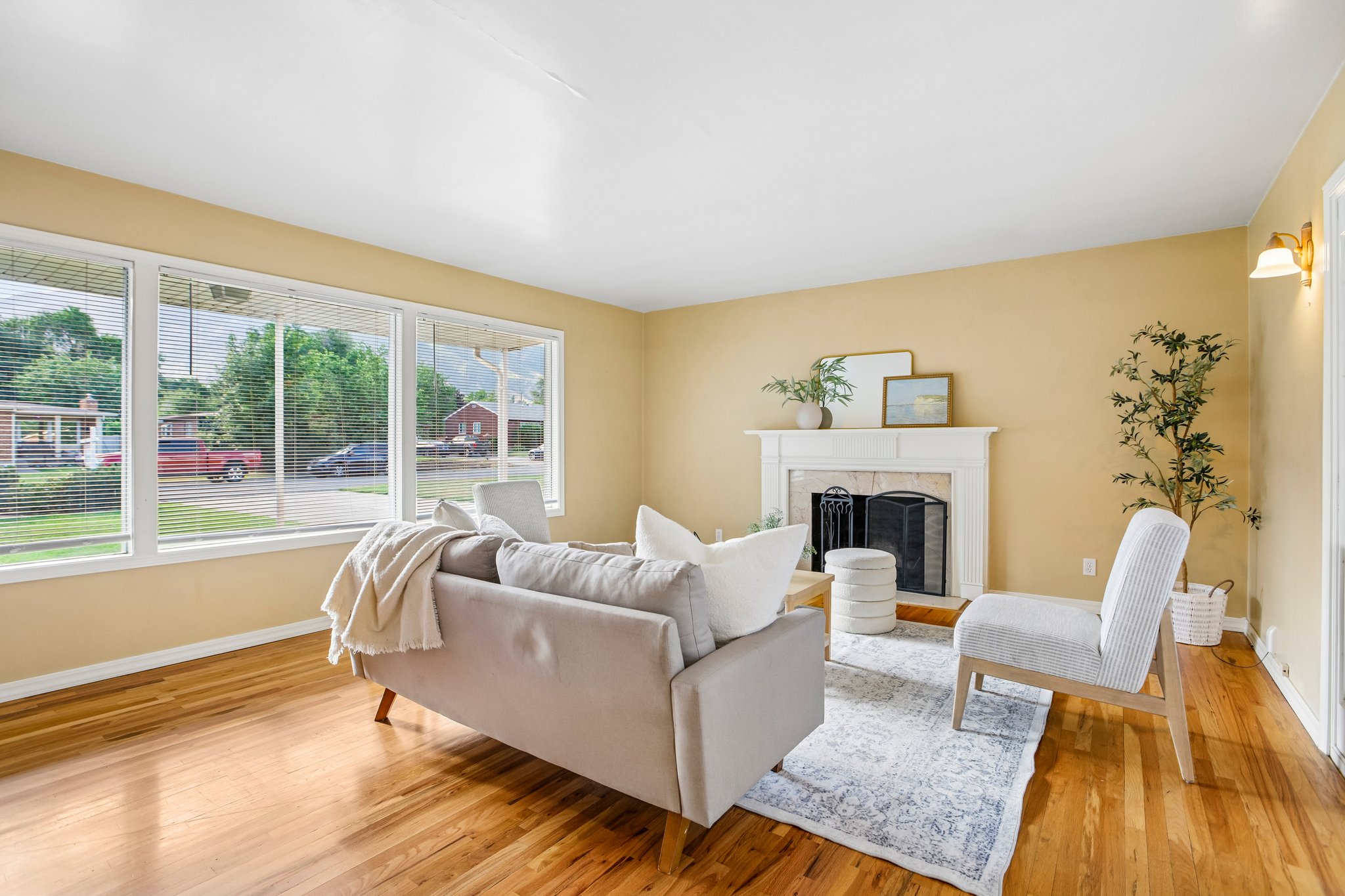Living area featuring wood-finish flooring, a white mantel fireplace, and a wall of windows