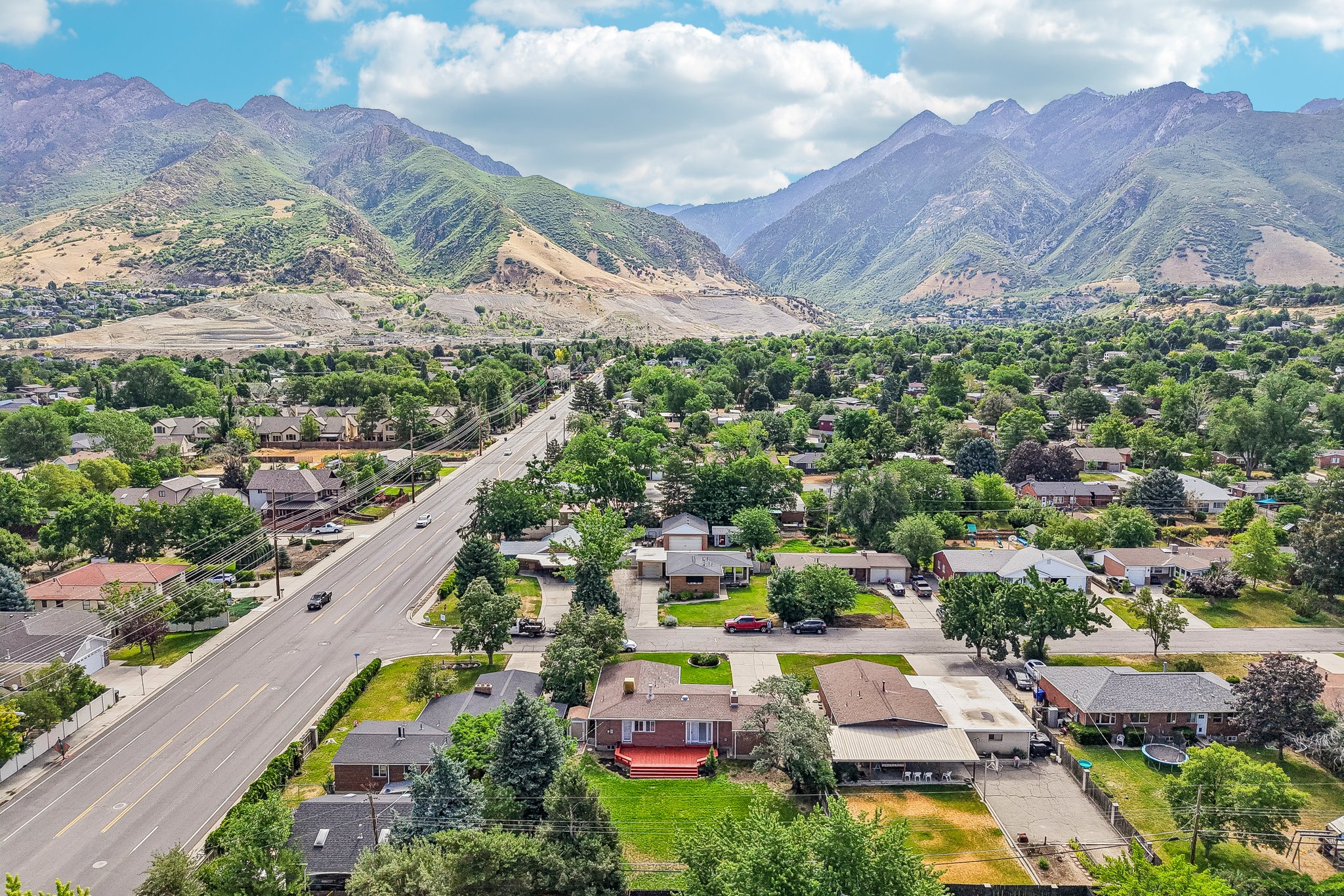 Expansive neighborhood featuring mature trees, residential homes, paved roads, and a mountainous backdrop