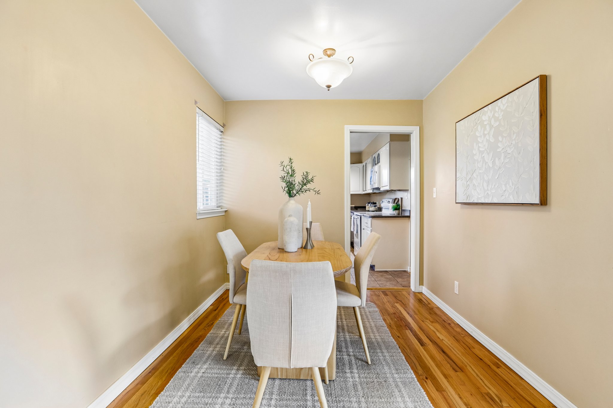 Dining area featuring wood-finish flooring, neutral wall tones, and a window with blinds