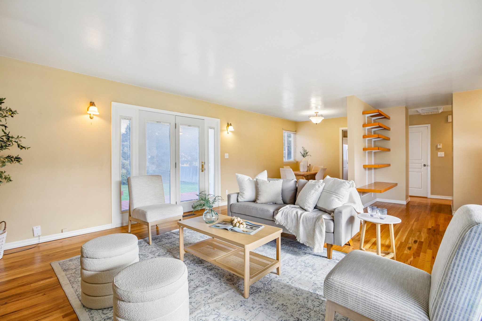 Living area featuring wood-finish flooring, light-toned walls, and a pair of white-framed glass French doors