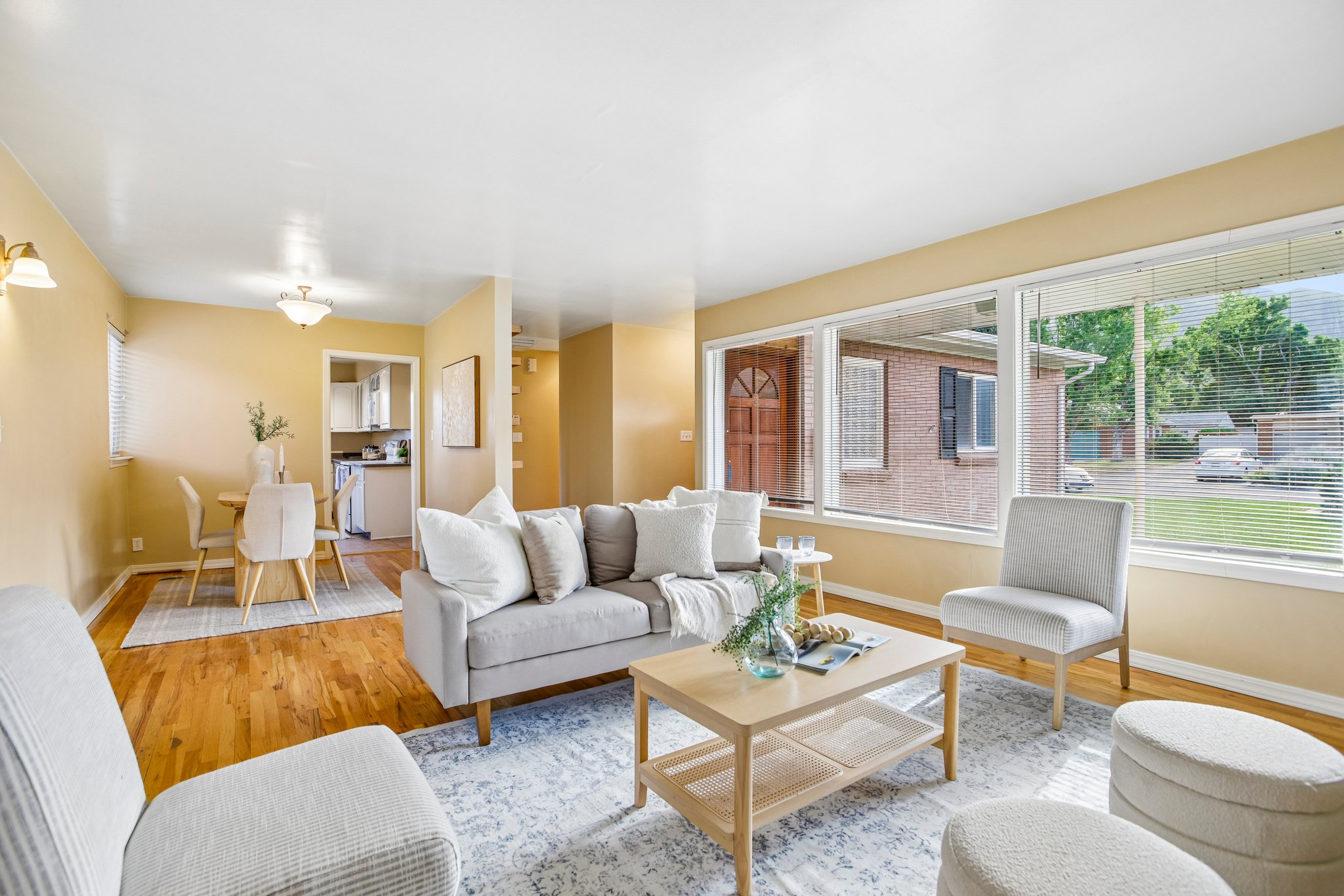 Bright living area featuring large windows, wood-finish flooring, and a dining space