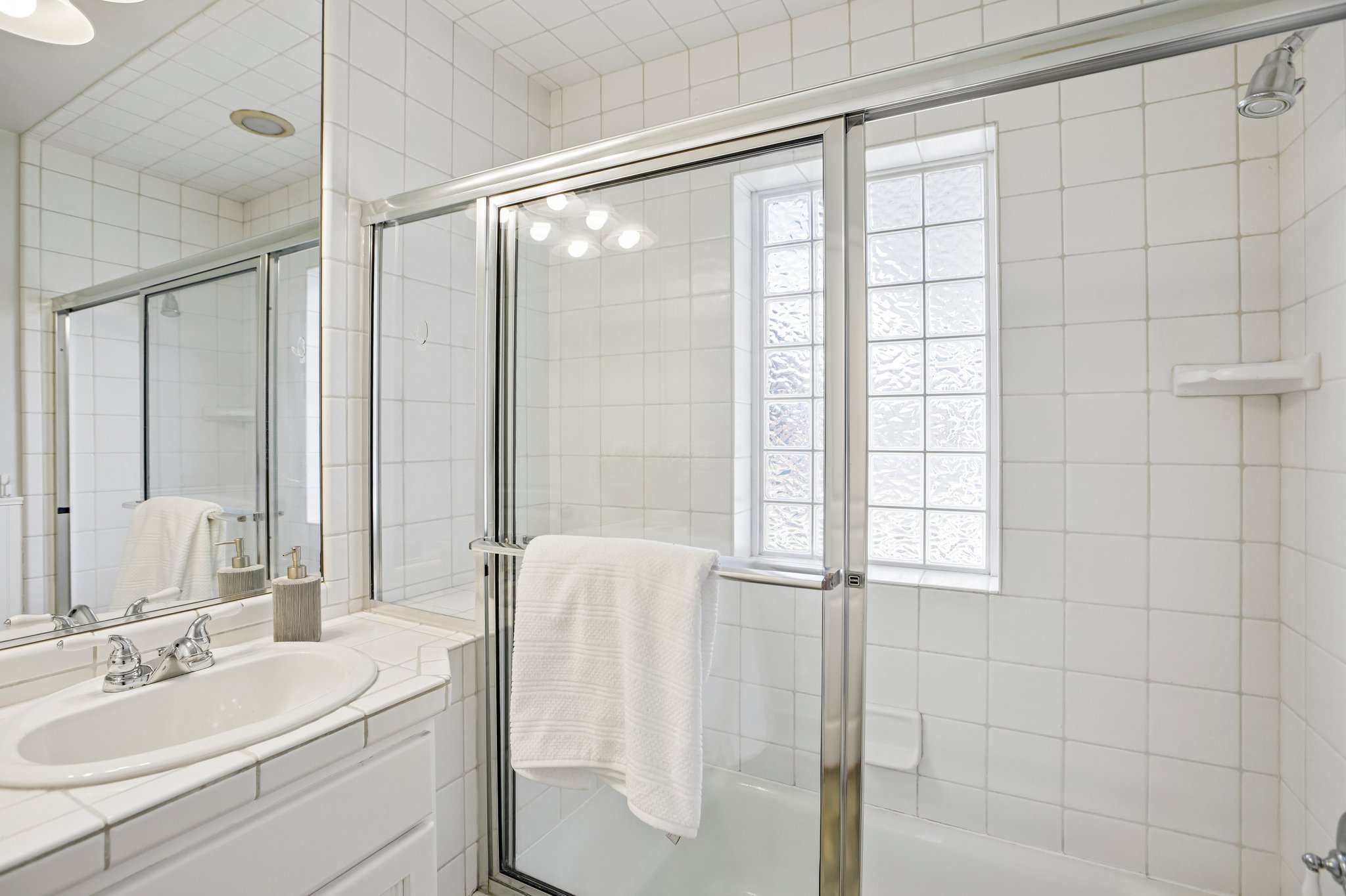 Bathroom featuring an integrated bathtub and shower with glass enclosure