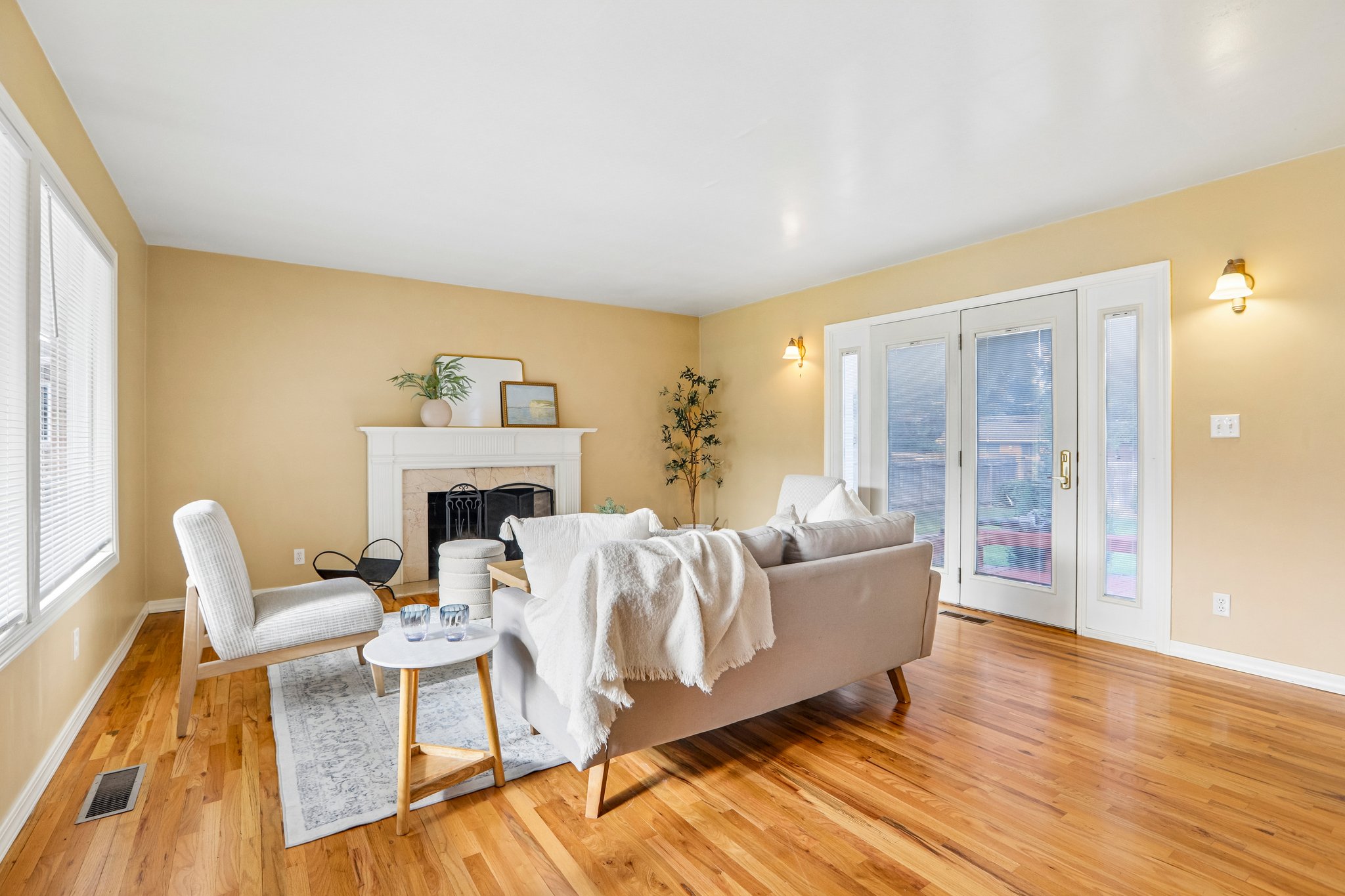 Living space featuring wood-finish flooring, a white mantel fireplace, and double glass doors