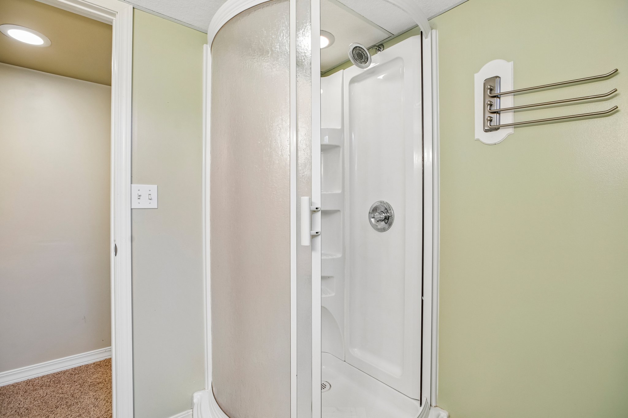 Curved glass-enclosed shower with white paneled interior