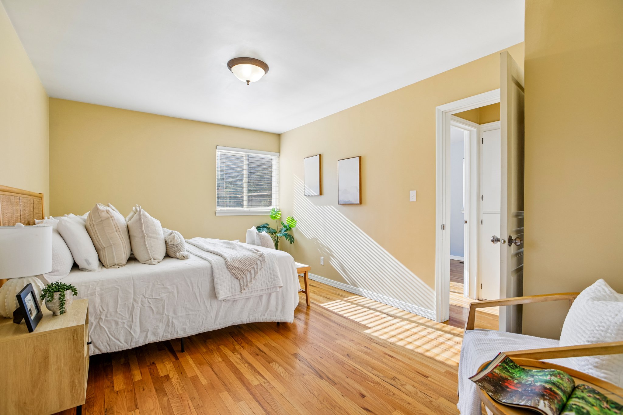 Bedroom with wood-finish flooring, a single window with blinds, and light-toned wall paint