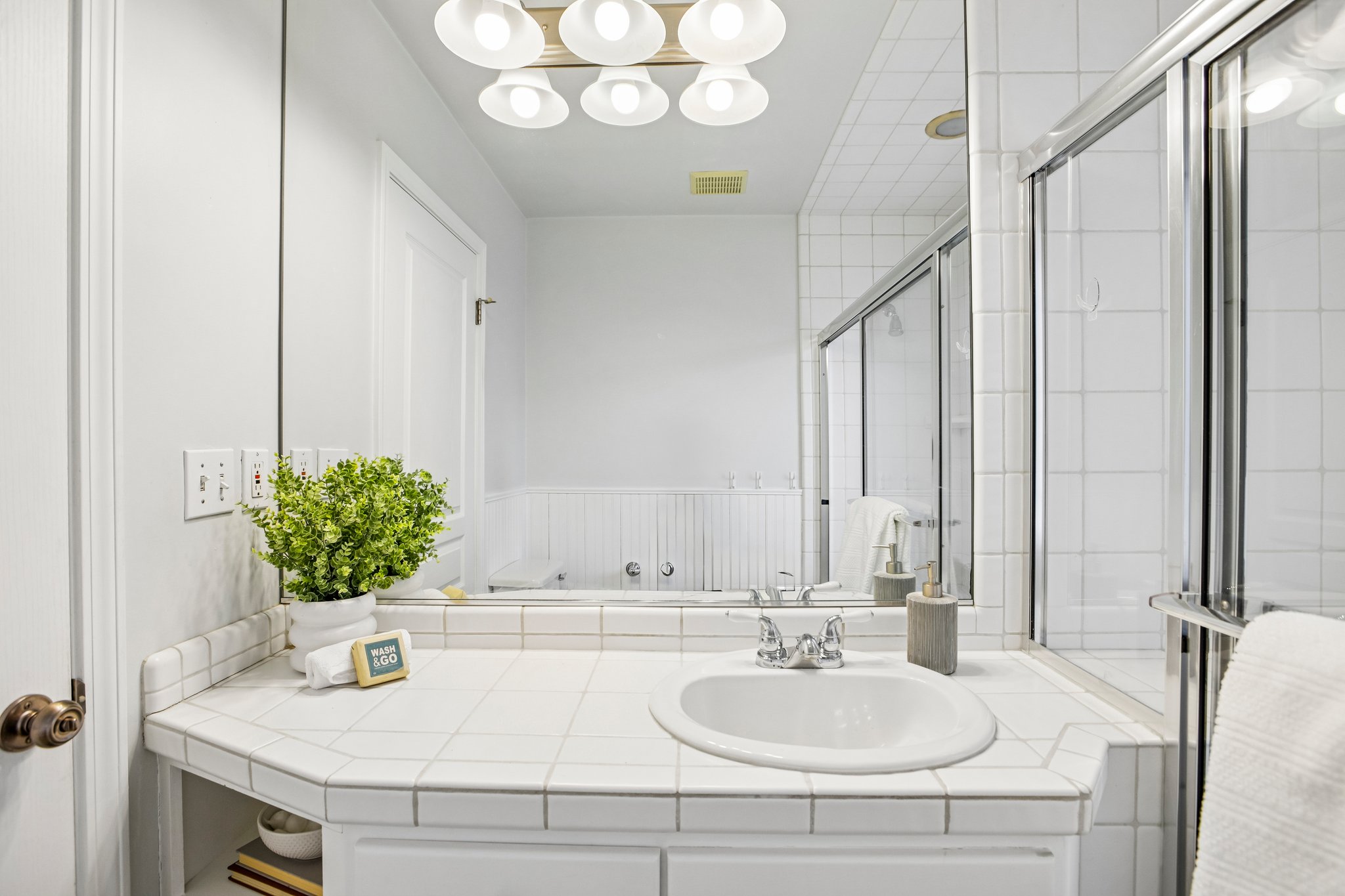 White tiled vanity with integrated sink and chrome fixtures