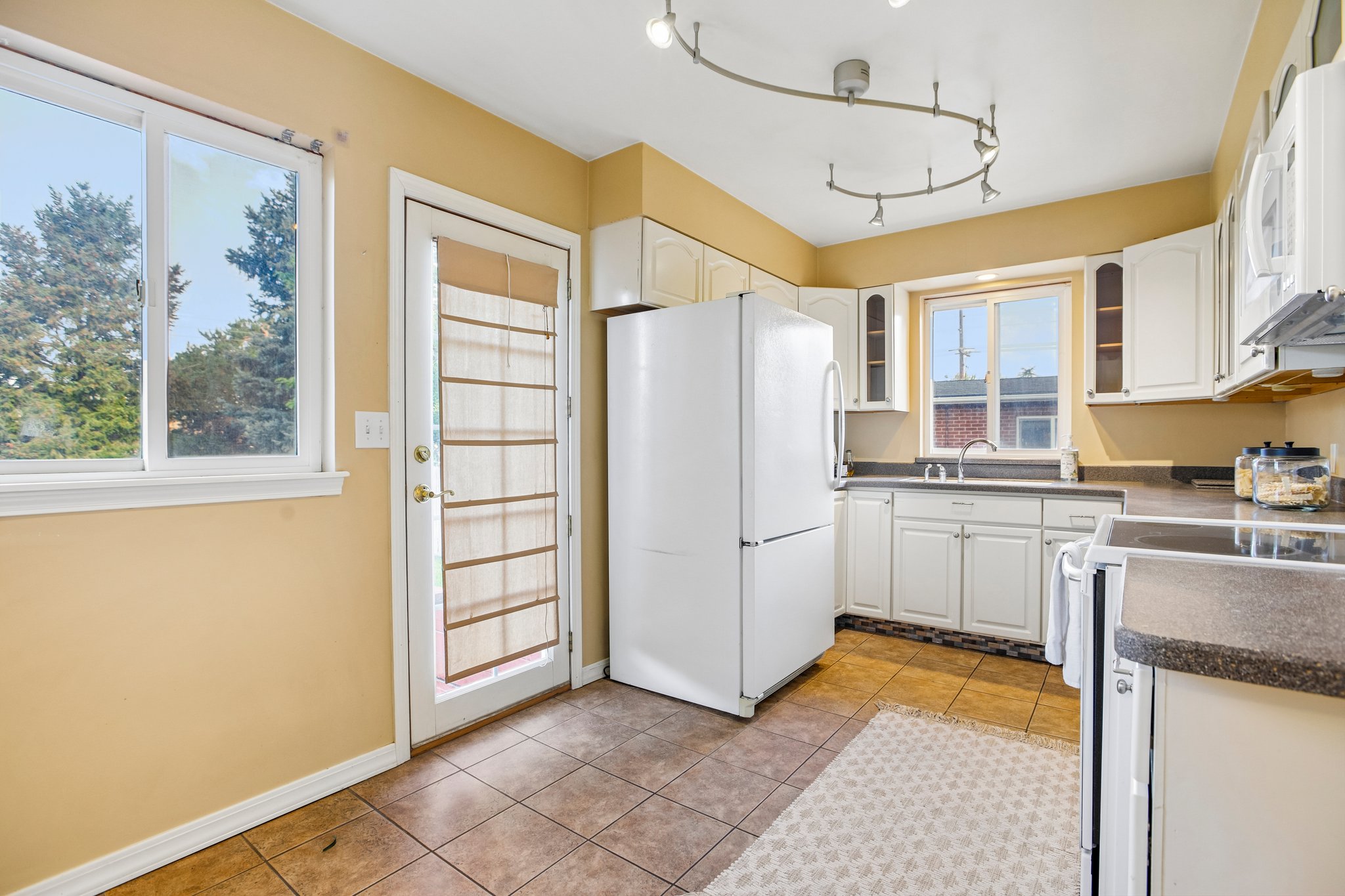 Kitchen featuring white cabinetry, track lighting, a full-size refrigerator, and dark countertops