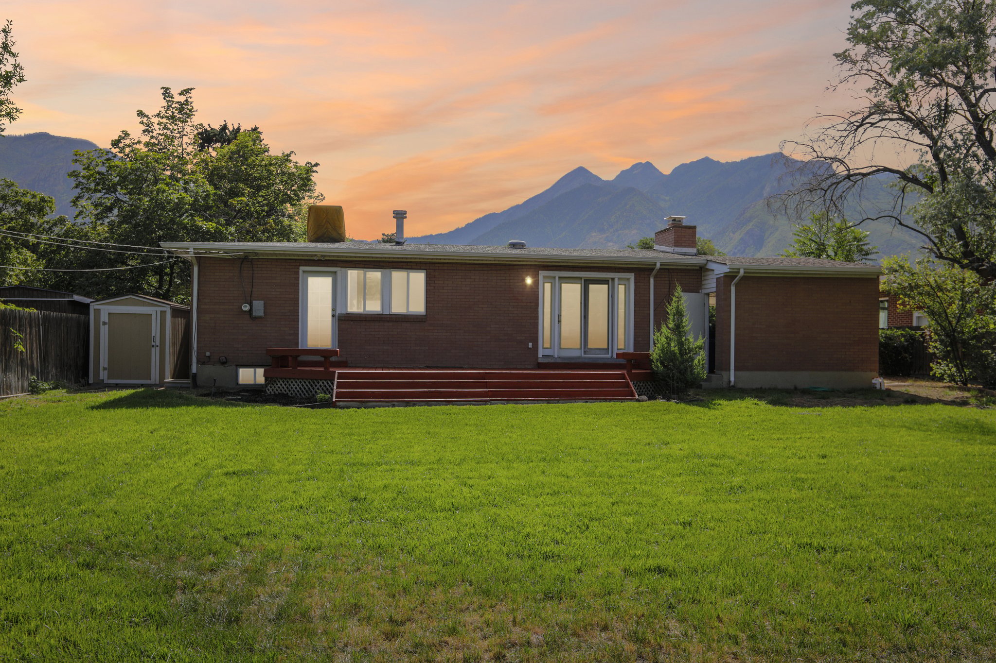 Expansive green lawn with a red-stained wood deck and French doors