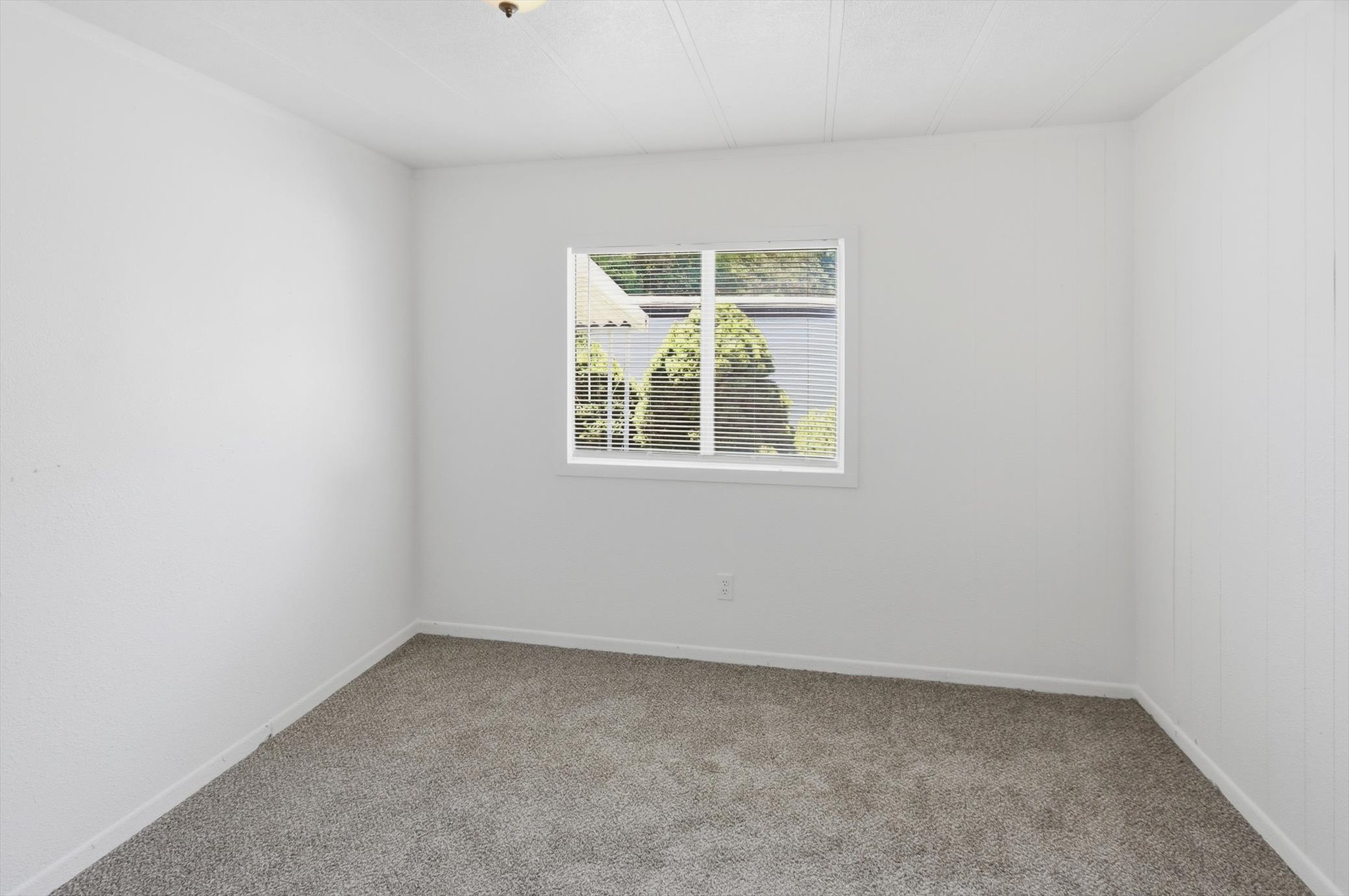 Room featuring neutral-toned carpeting, white painted walls, and a single window with horizontal blinds