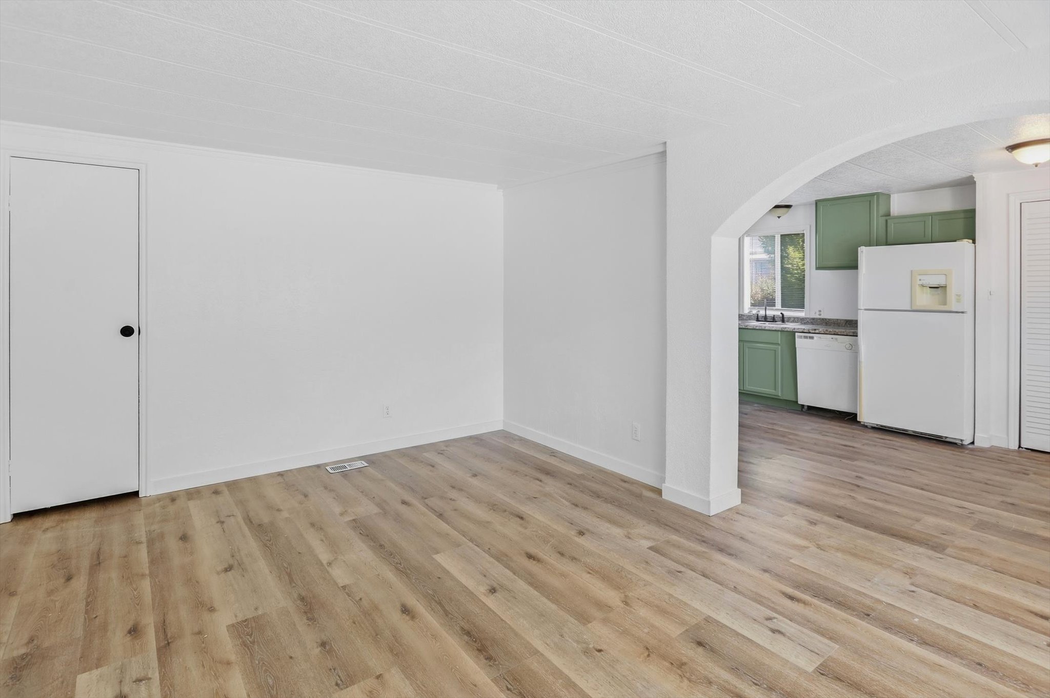 Bright interior space featuring wood-finish flooring, white walls, and a recessed air vent