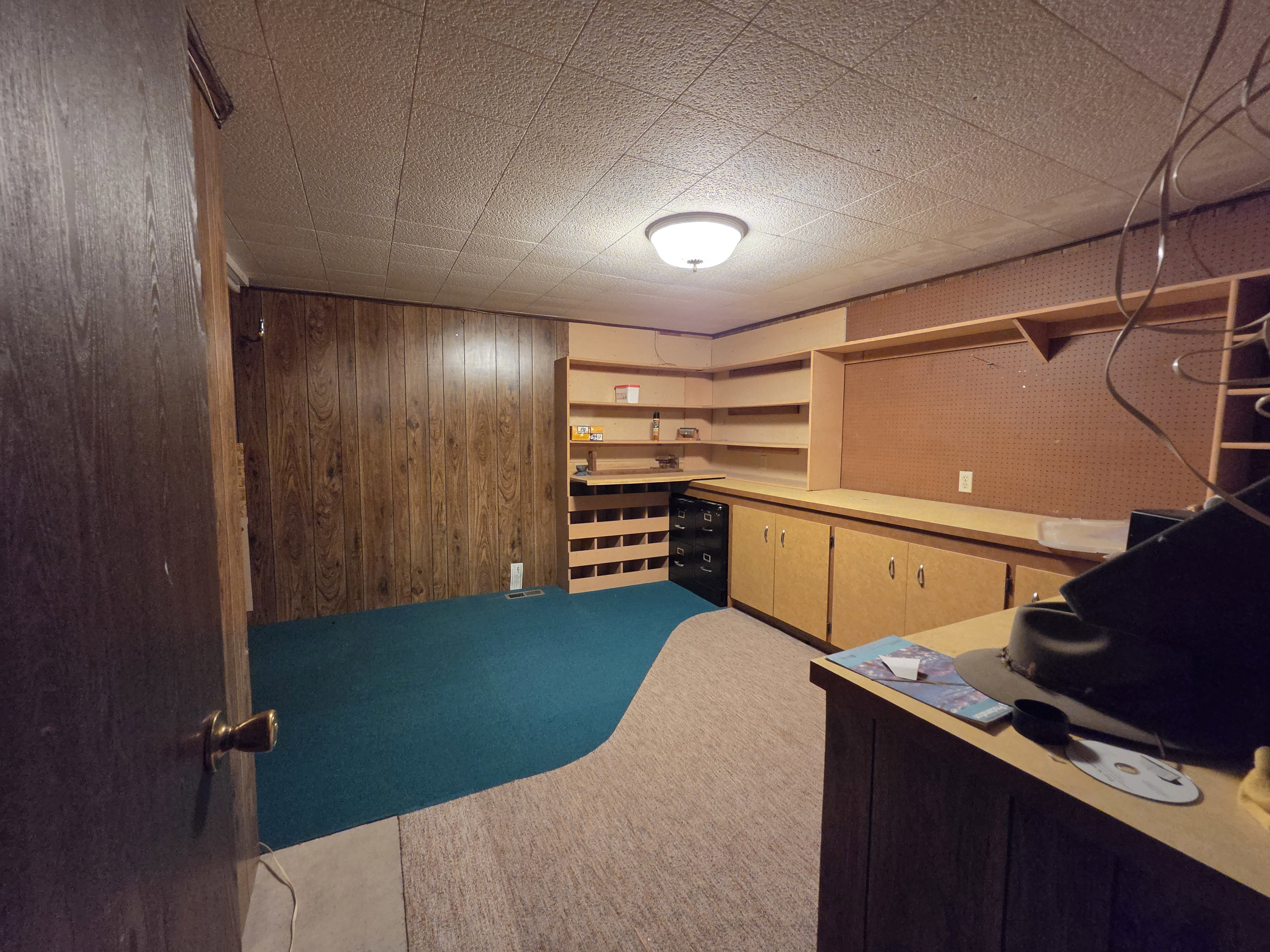 Finished room featuring wood-finish wall paneling, built-in shelving, and extensive cabinetry with an integrated workspace
