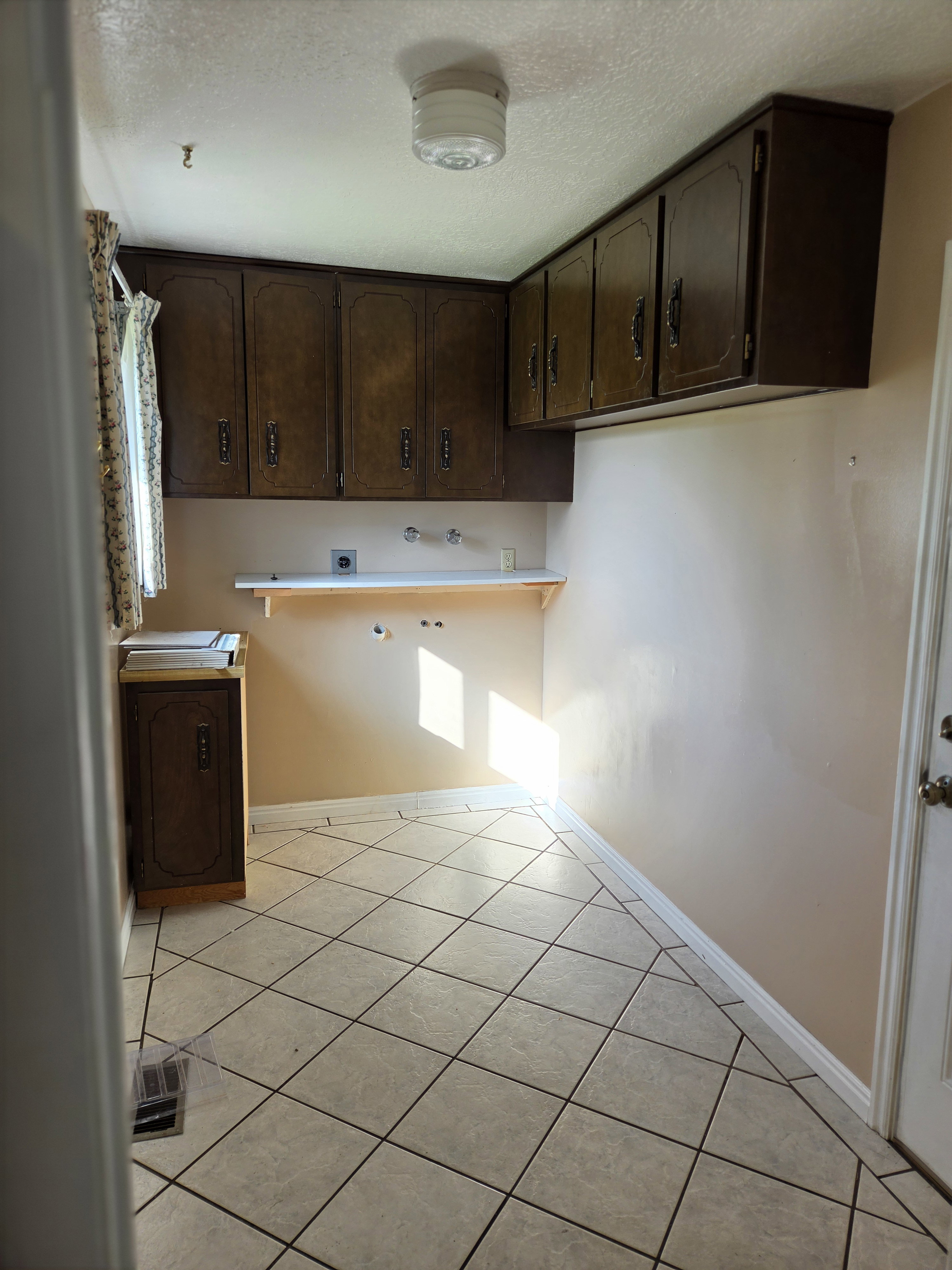 Utility room featuring diagonal tile flooring, extensive wall cabinetry, a built-in shelf, and ceiling-mounted lighting