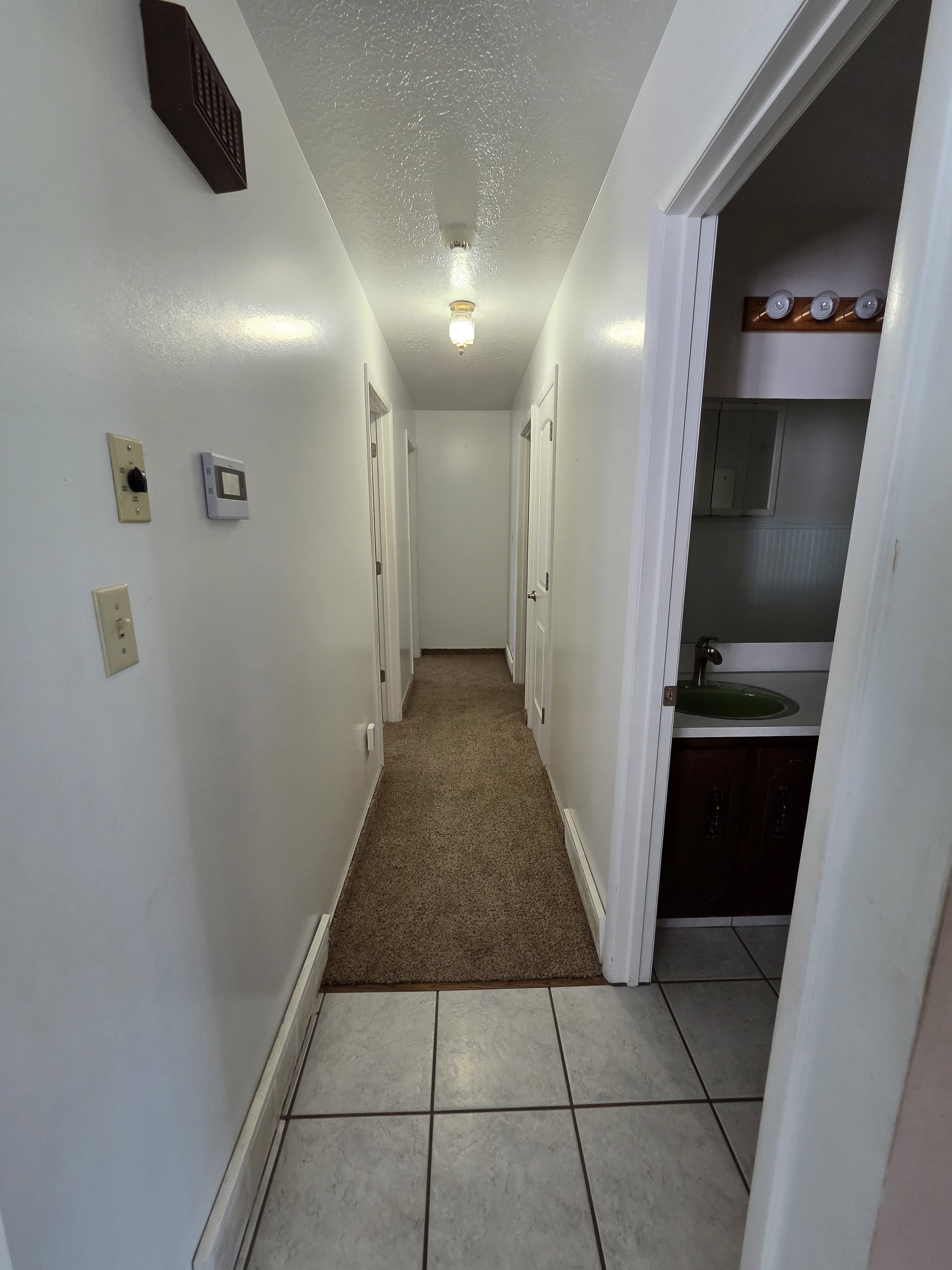 Hallway featuring neutral carpet and overhead lighting