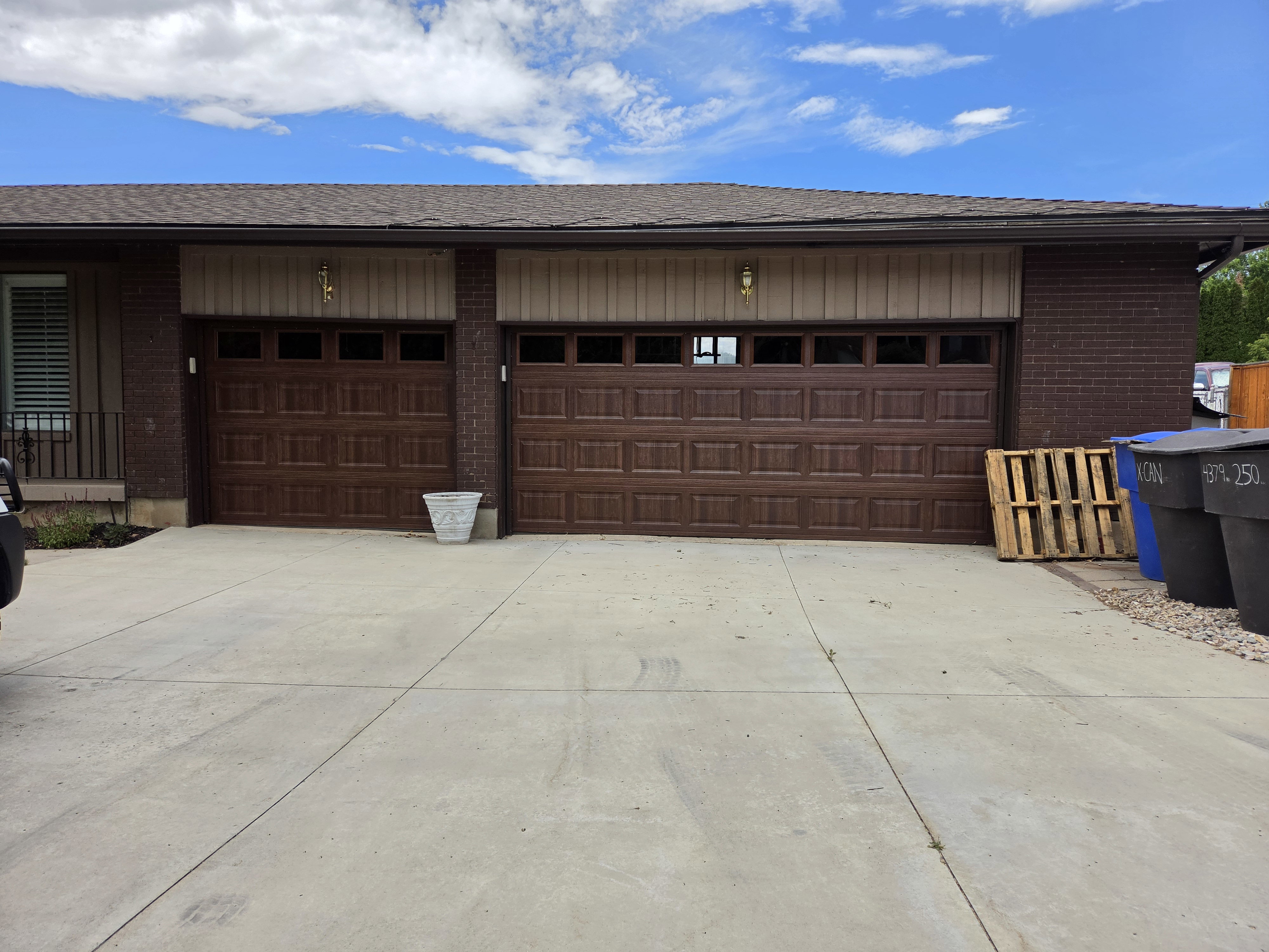 Two brown paneled garage doors featuring window inserts