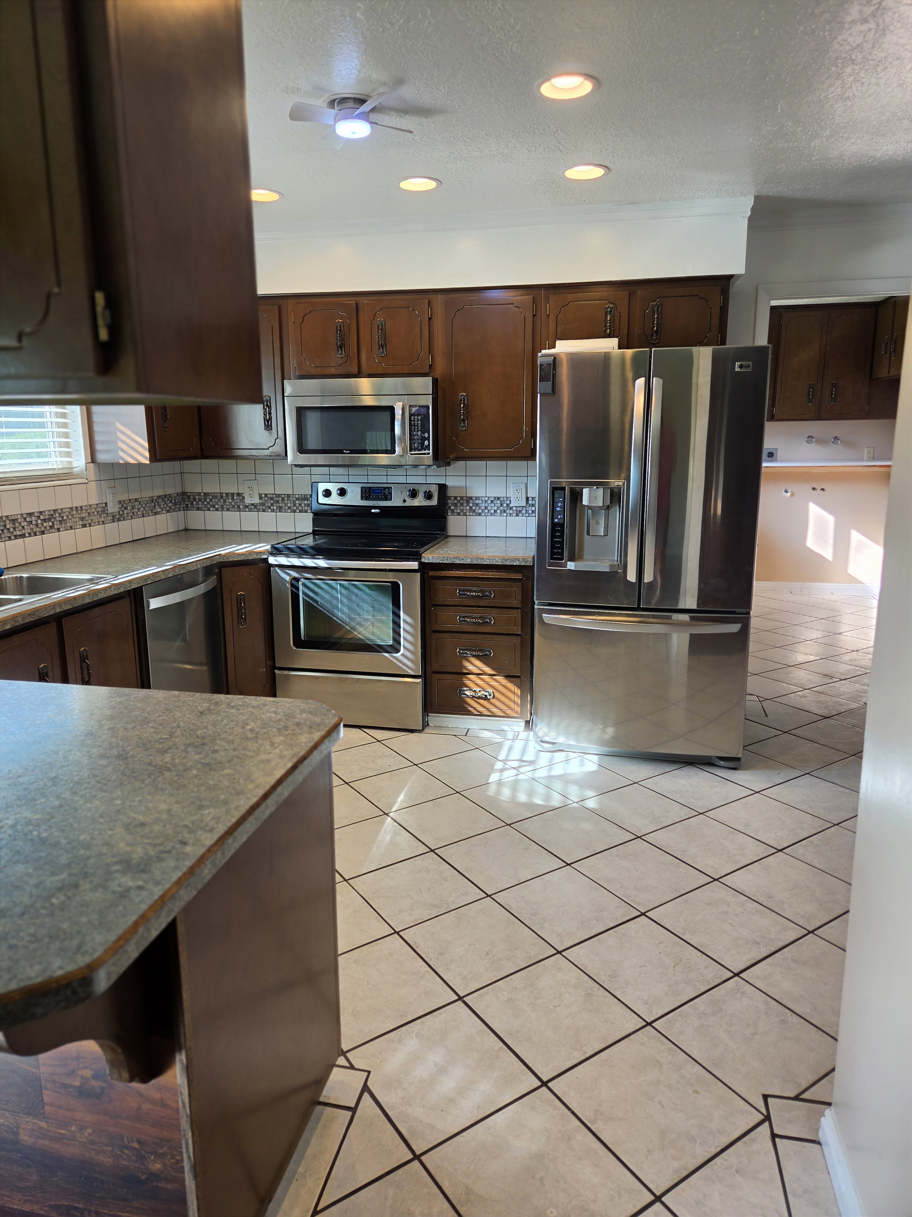 Kitchen featuring stainless steel appliances, dark wood cabinetry, and a tile backsplash with decorative accents