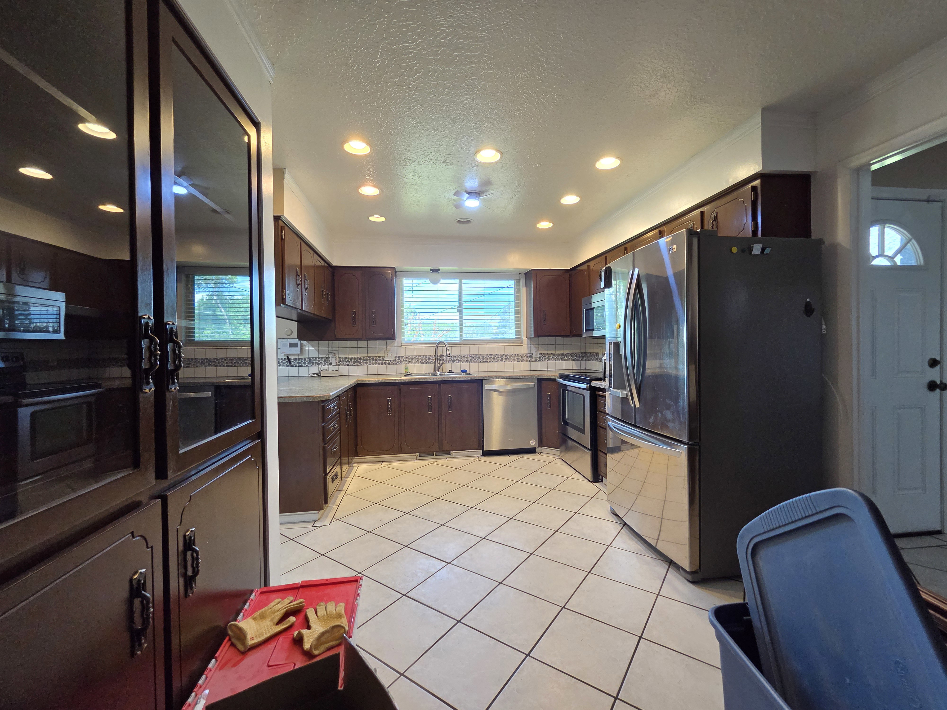 Kitchen featuring stainless steel appliances, dark wood cabinetry, white tile flooring, and recessed lighting