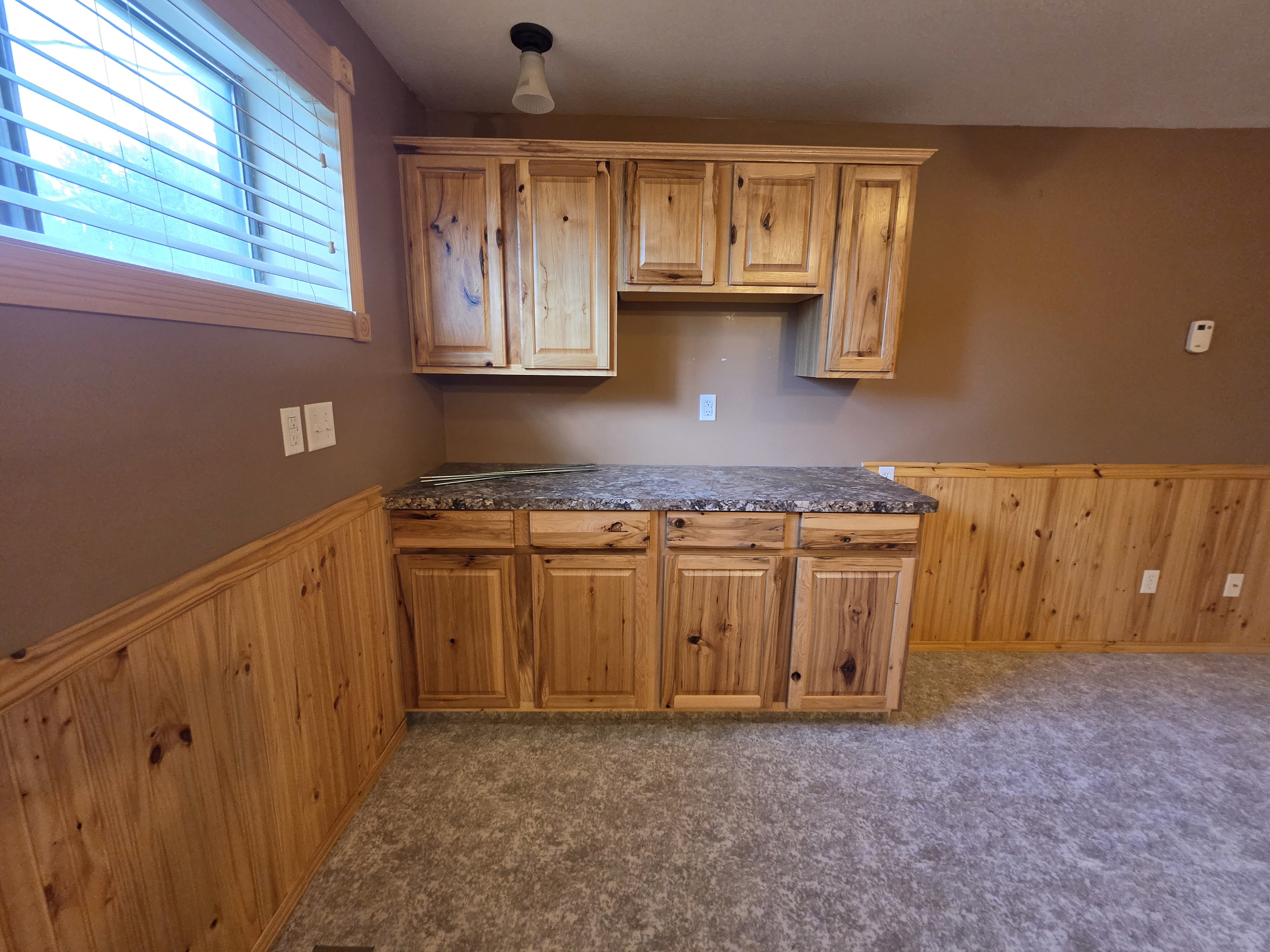 Built-in cabinetry with natural wood-grain finish and dark speckled countertop