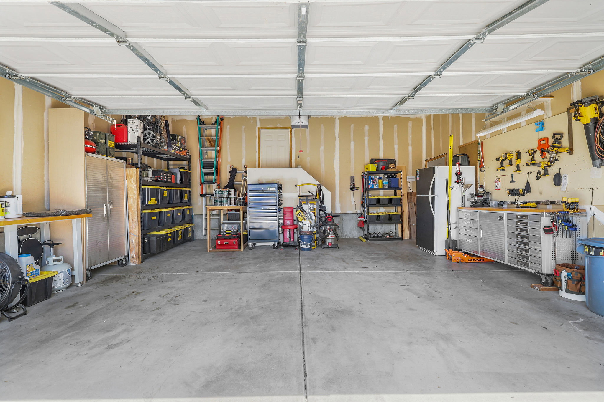 Spacious garage featuring a concrete floor, exposed ceiling joists, and direct interior access