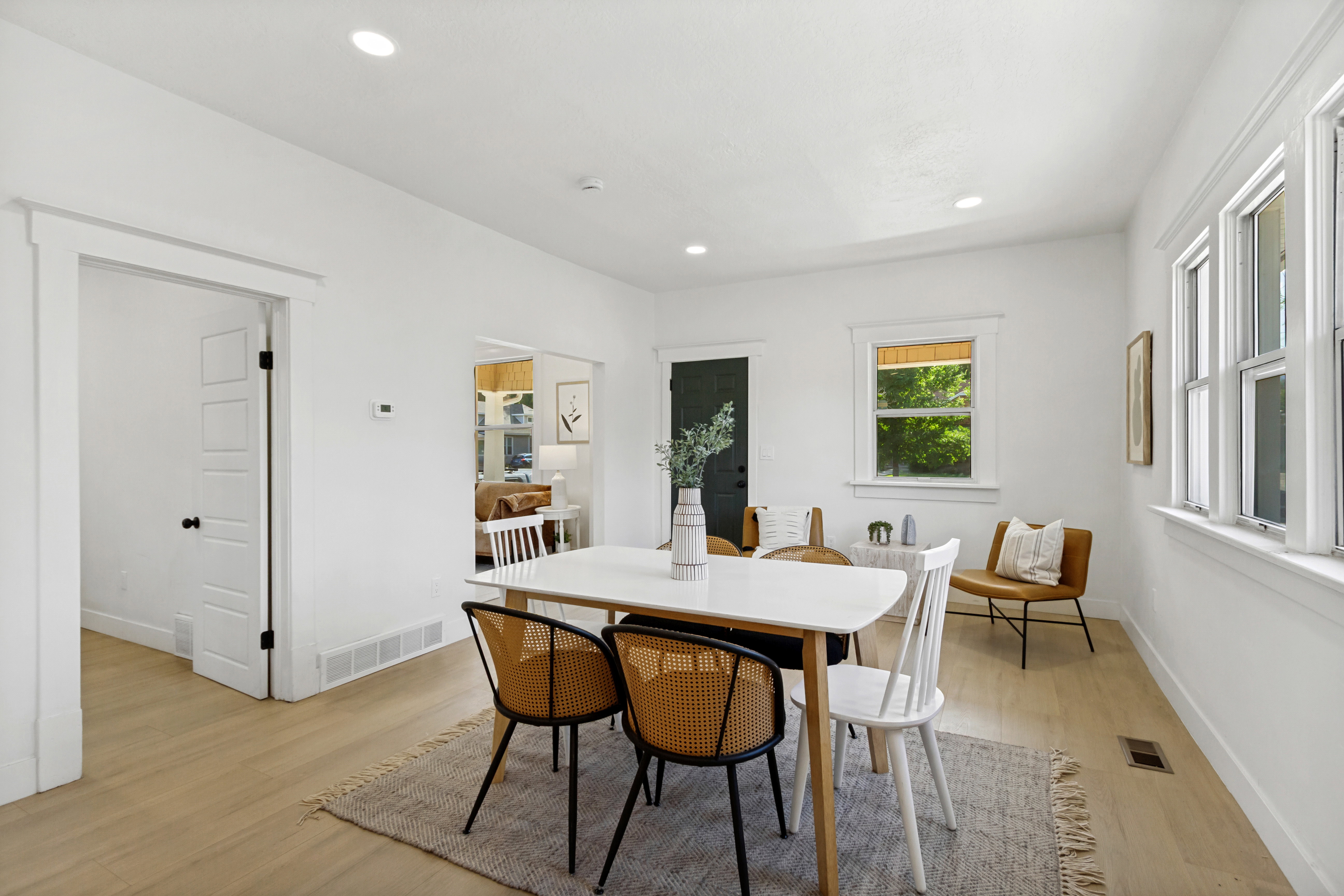 Open-concept space featuring light wood-finish flooring, white walls, recessed lighting, and ample natural light from multiple windows