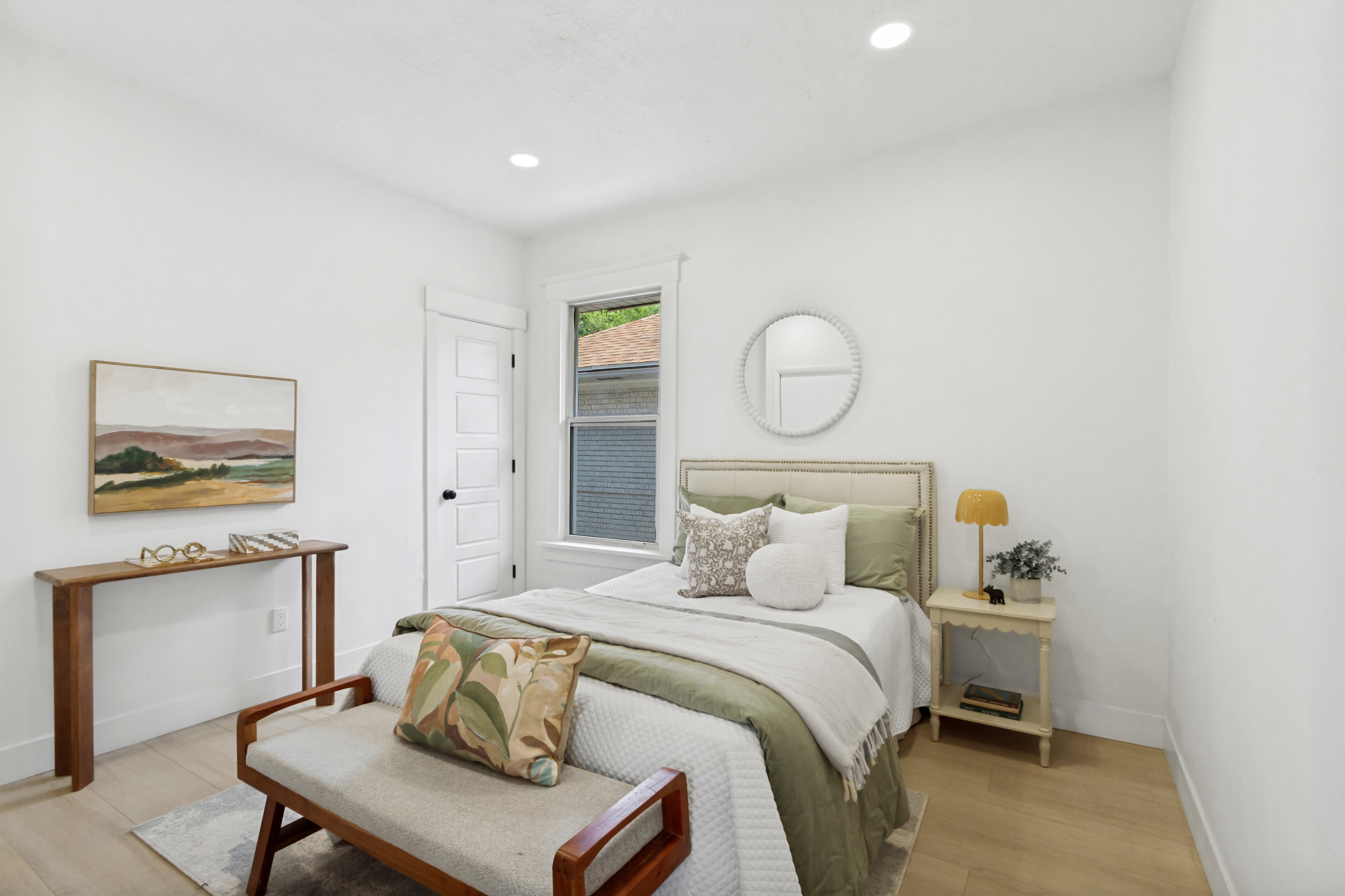 Bright interior space featuring light wood-finish flooring, recessed lighting, a window with exterior views, white trim, and a paneled door