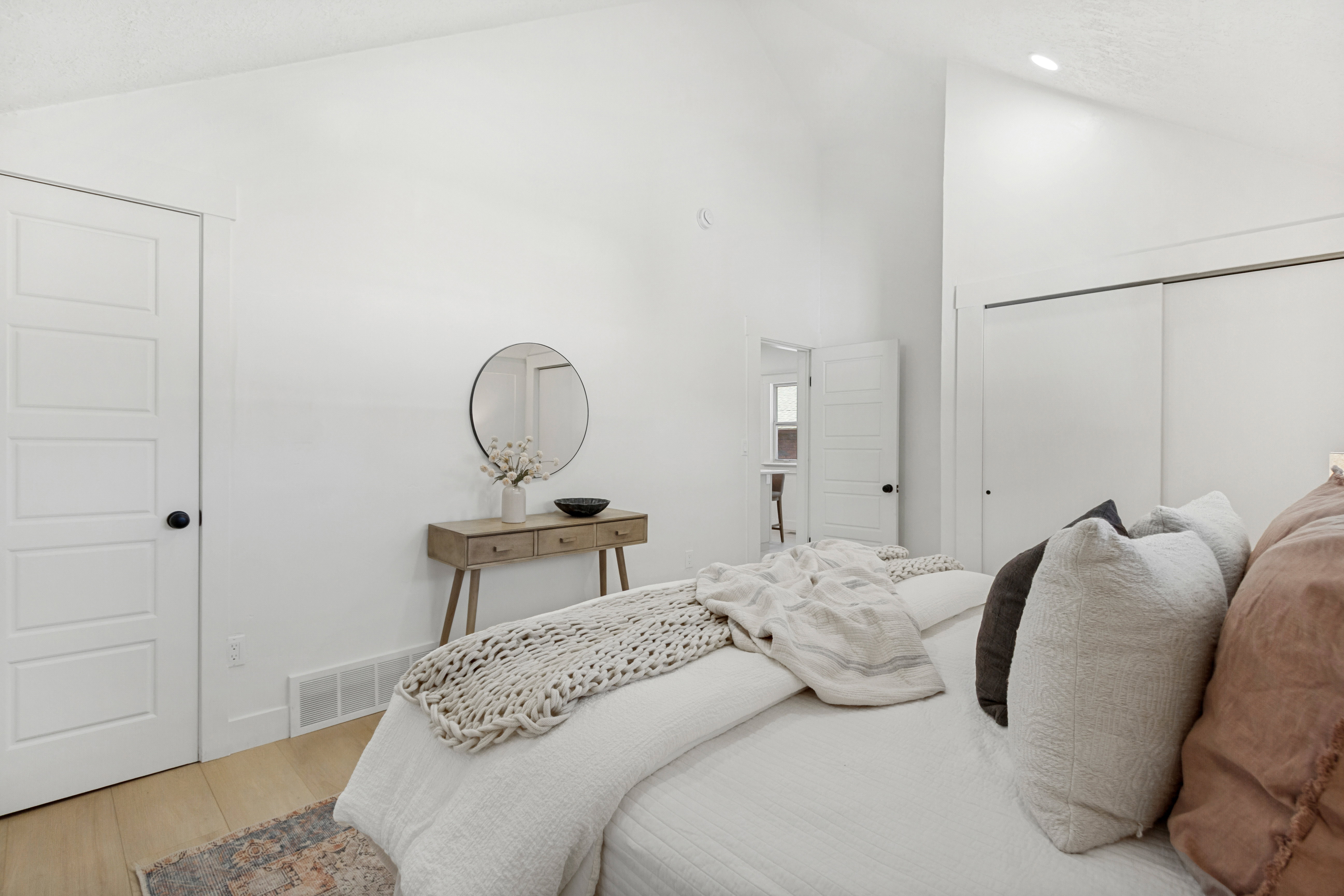 Vaulted ceiling bedroom featuring white walls, five-panel interior doors with black hardware, wood-finish flooring, and sliding closet doors