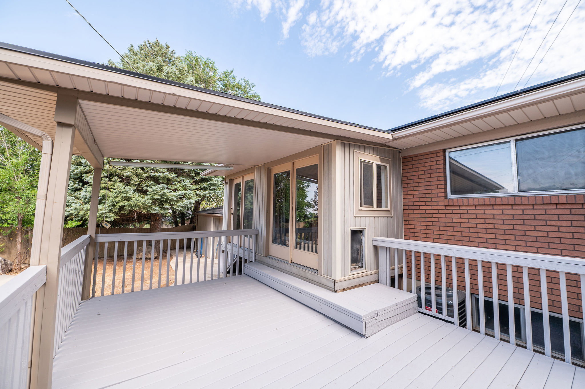Covered deck with painted wood-finish flooring and white railings