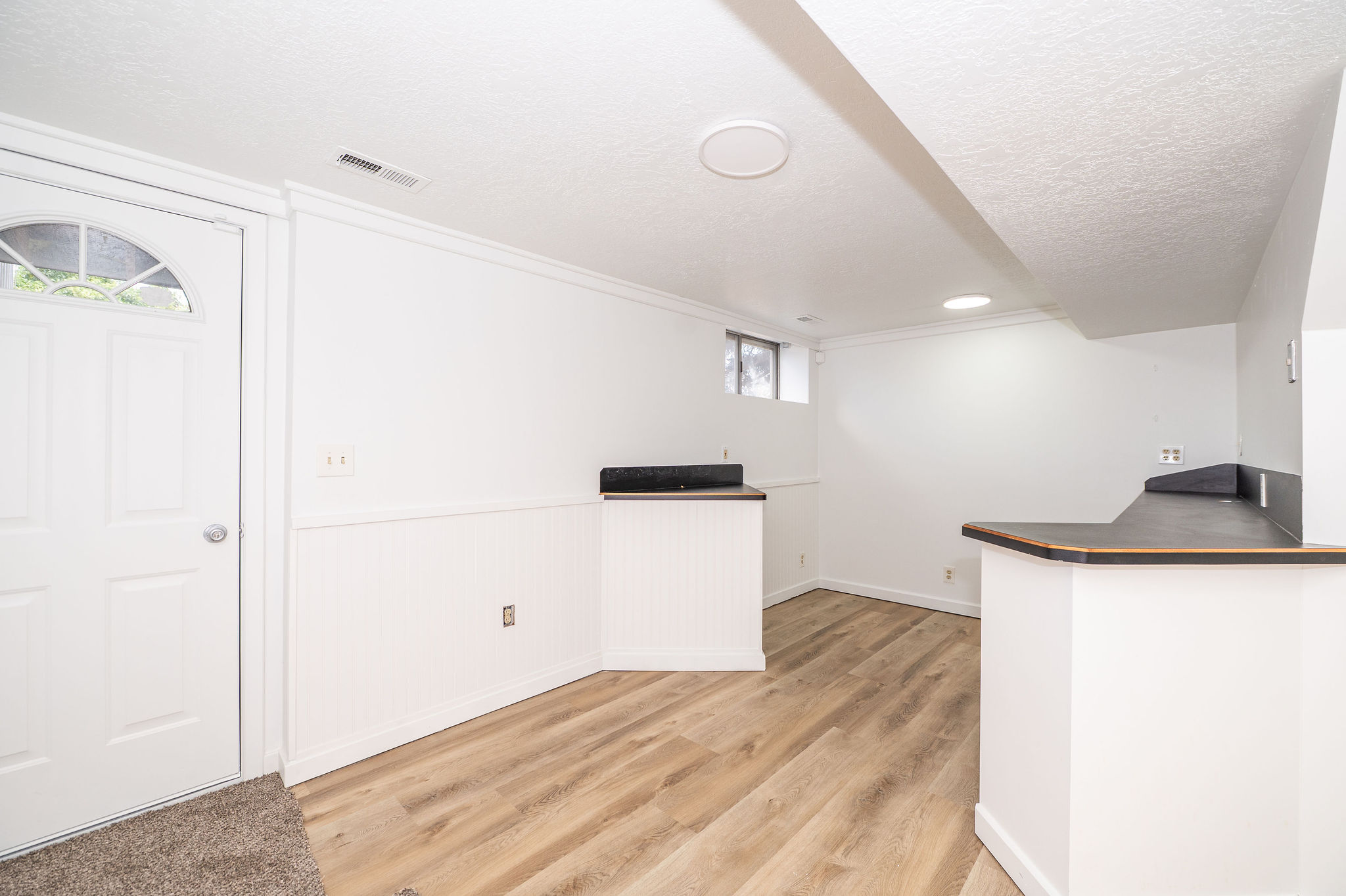 Finished lower level with wood-finish flooring and white wainscoting