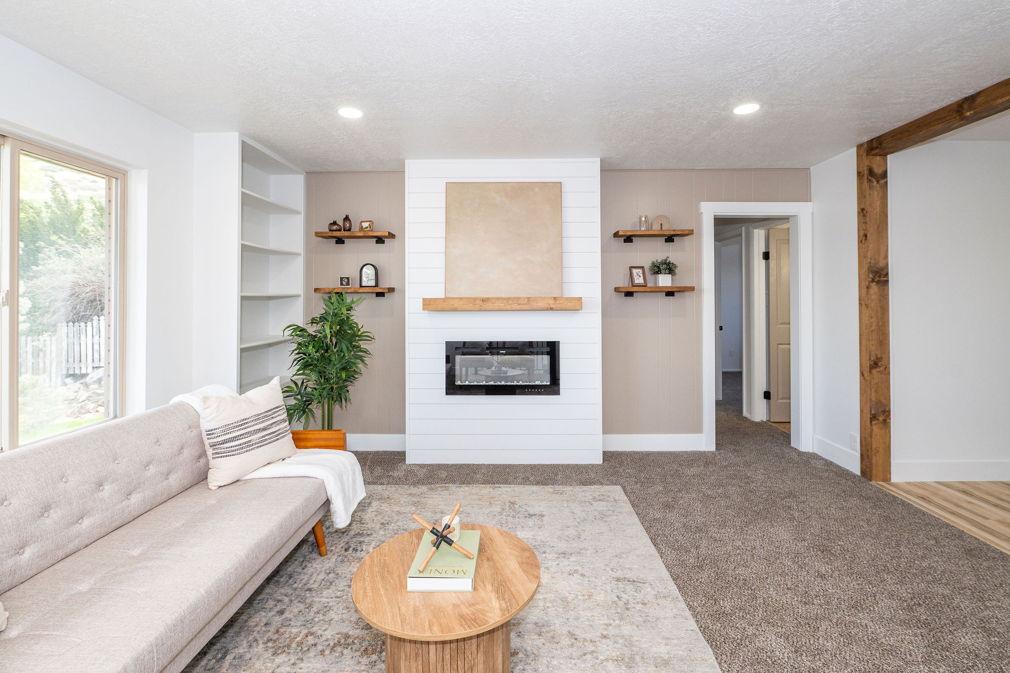 Spacious living area featuring a modern electric fireplace with shiplap surround, a substantial wood mantel, recessed lighting, built-in shelving, and warm wood-finish flooring