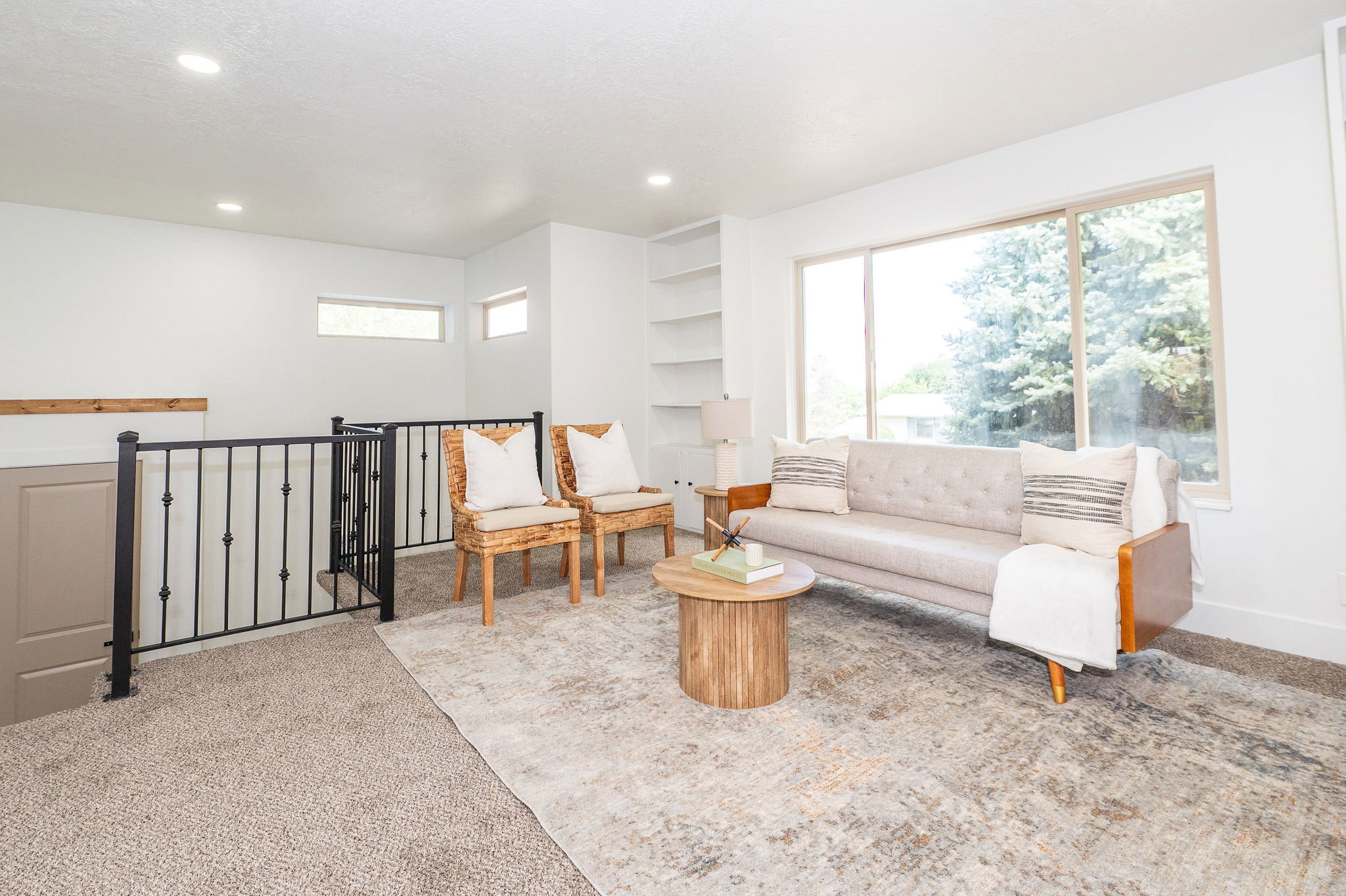 Open loft area featuring a large picture window, recessed lighting, built-in shelving, and a black wrought iron railing