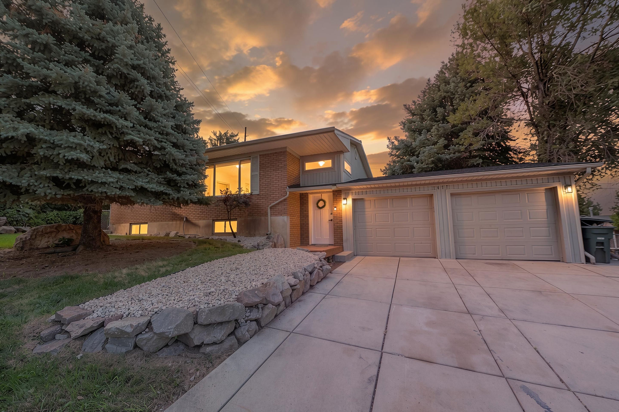 Brick and siding exterior featuring large windows, a concrete driveway, and a two-car garage