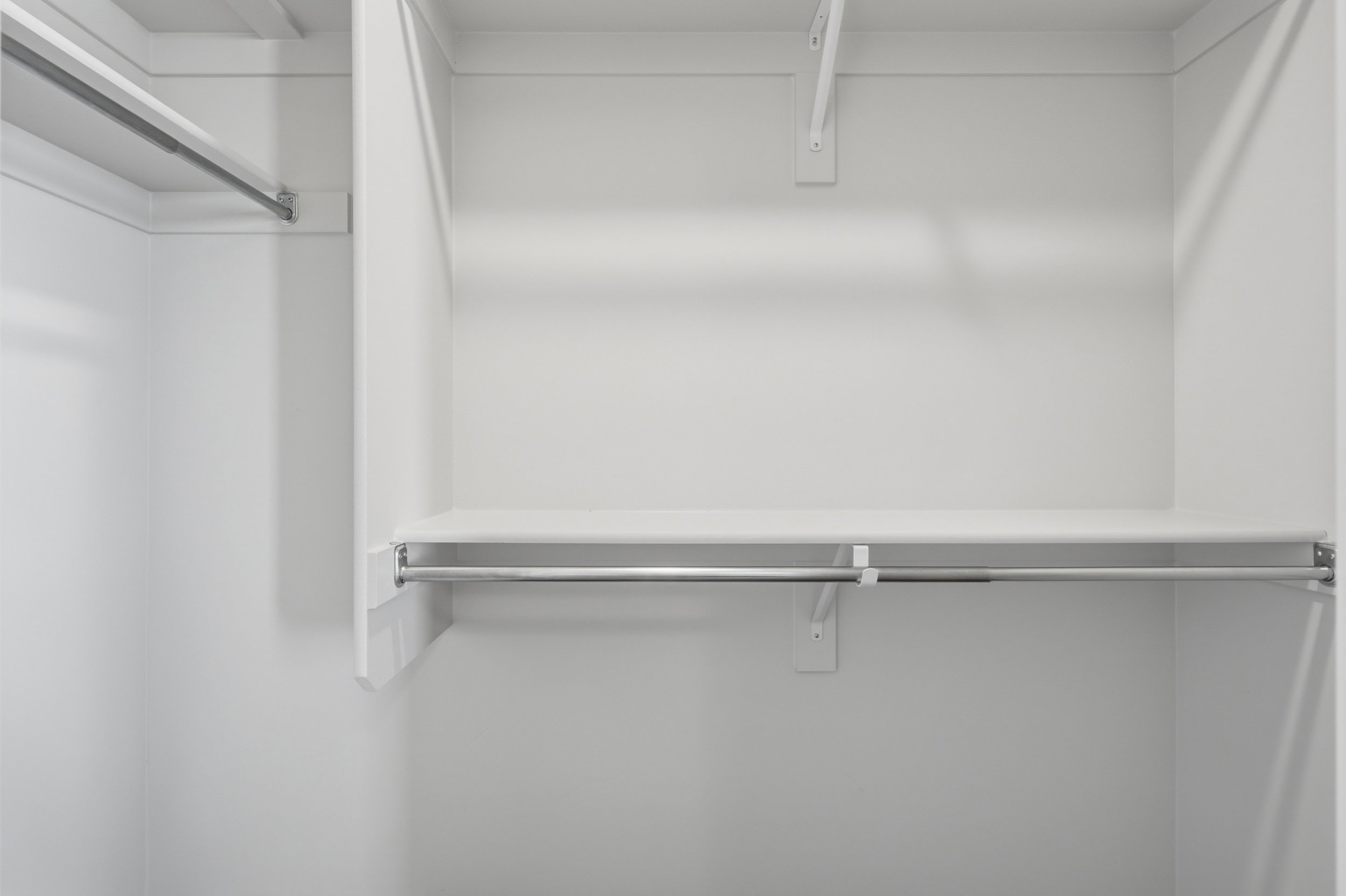 Closet system featuring multiple storage shelves and chrome hanging rods