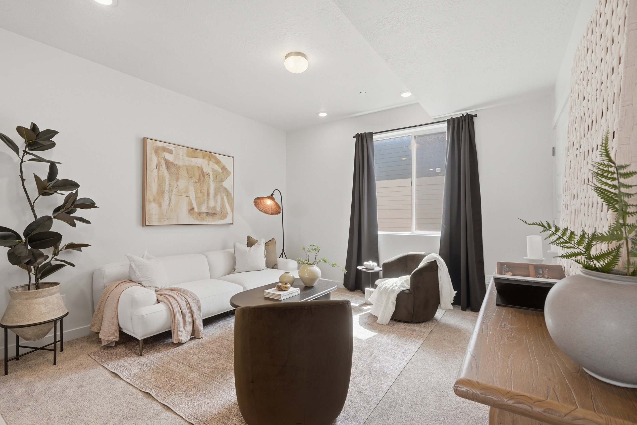 Bright living area featuring recessed lighting, a large window with dark drapes, and a decorative wall panel