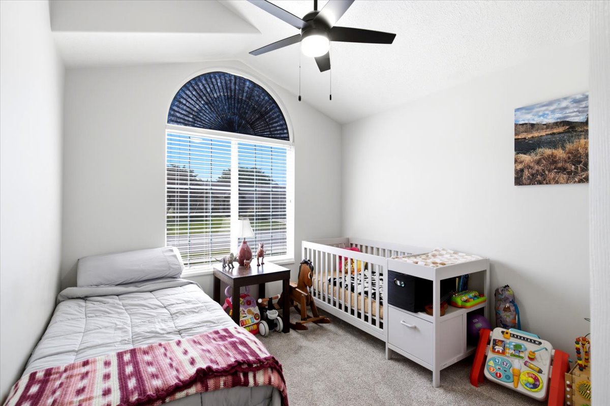 Bedroom featuring a vaulted ceiling and a large arched window with blinds
